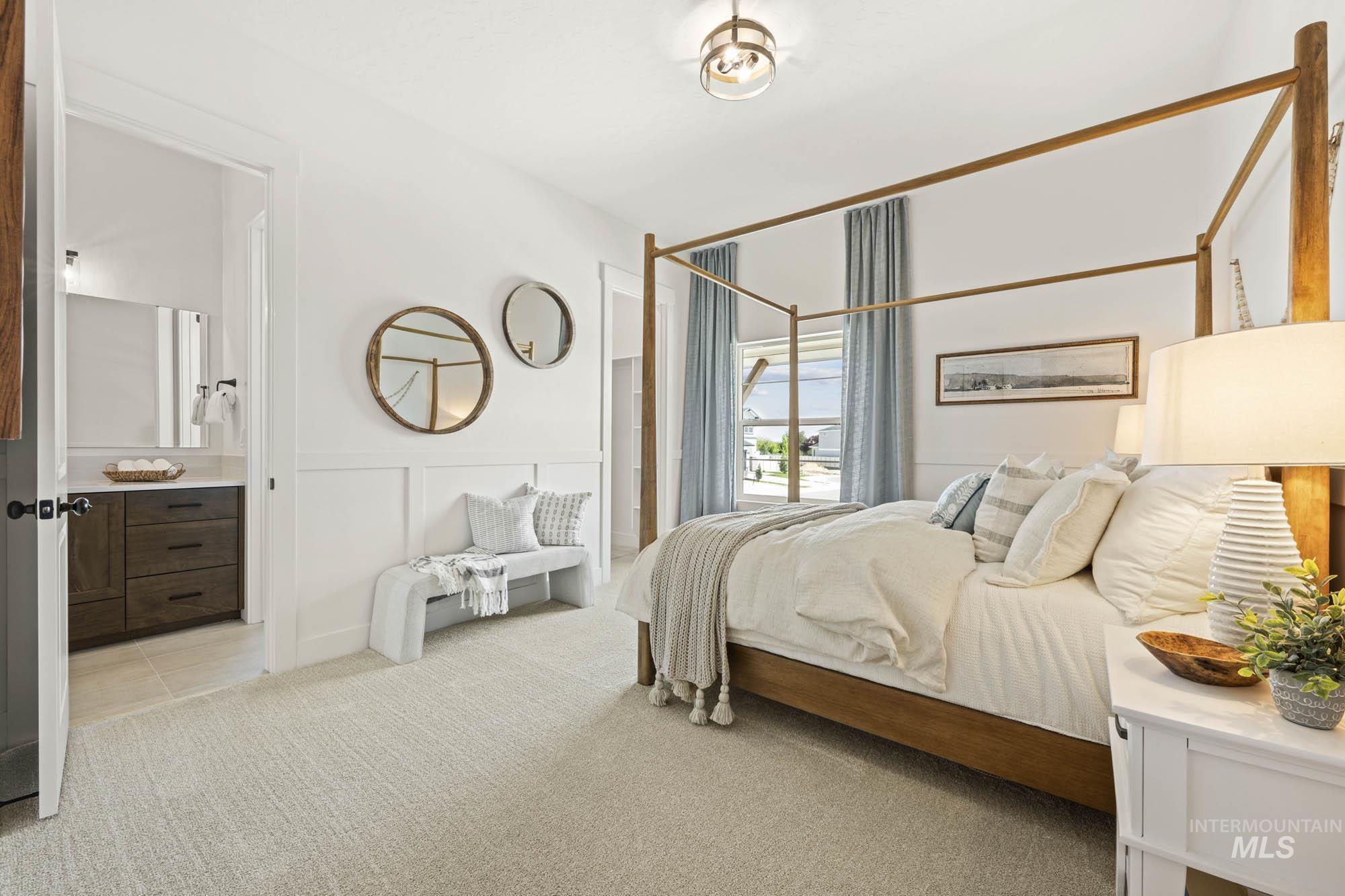 Bedroom featuring light colored carpet, ensuite bath, a decorative wall, and wainscoting