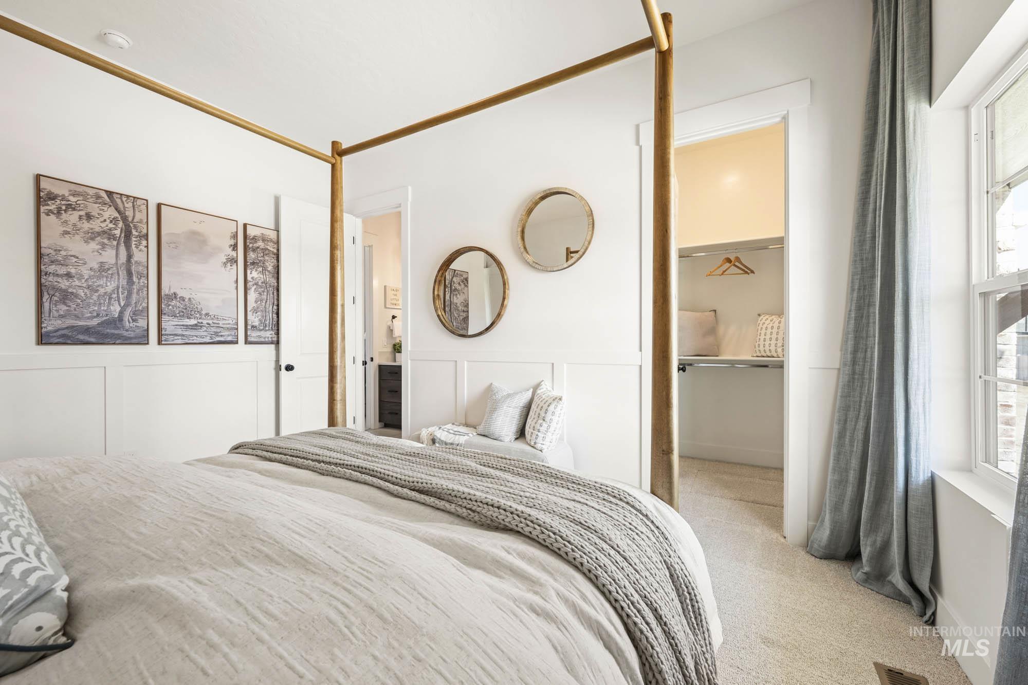 Bedroom featuring light colored carpet and a decorative wall