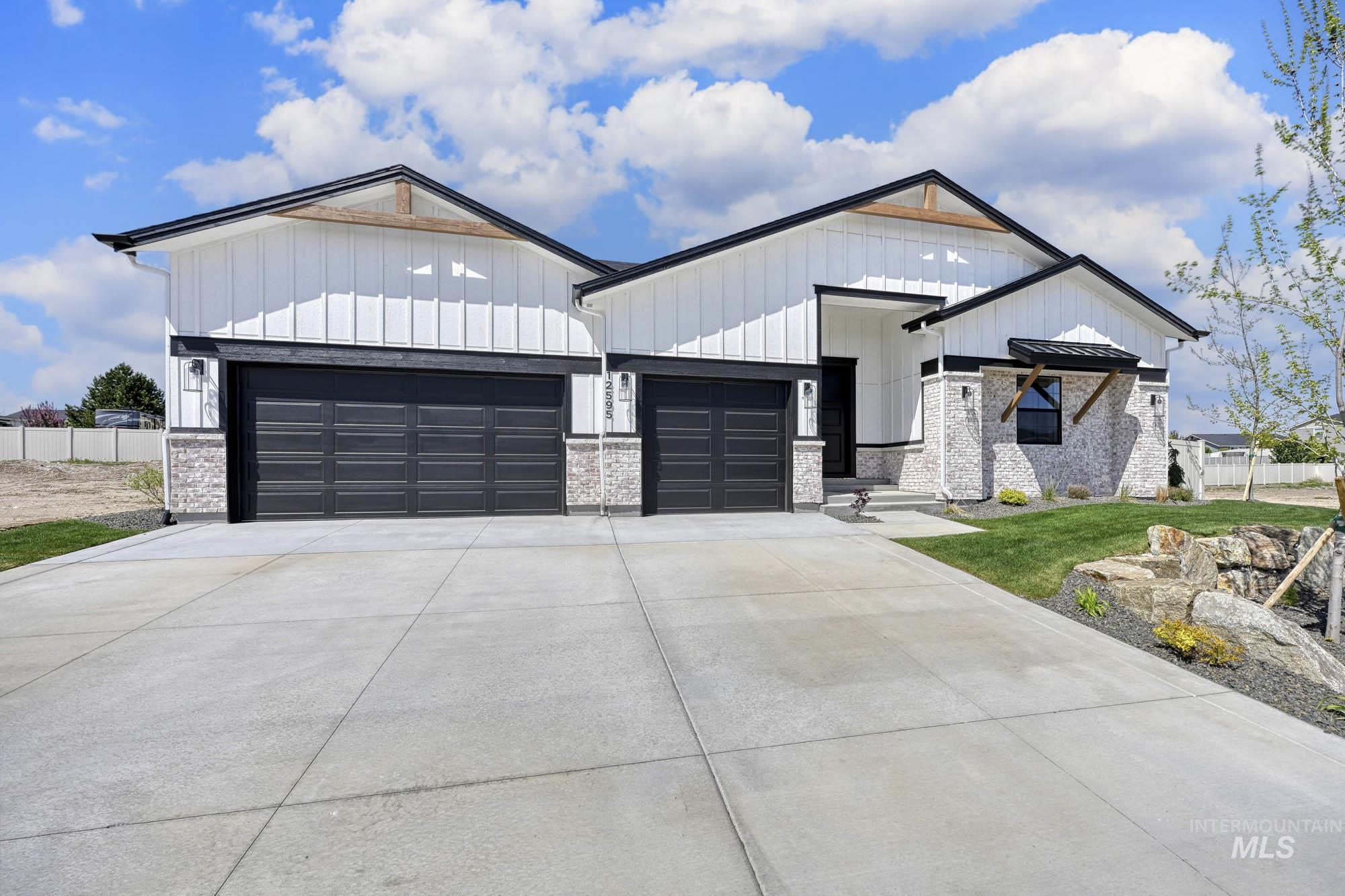 Modern inspired farmhouse featuring concrete driveway, board and batten siding, and an attached garage