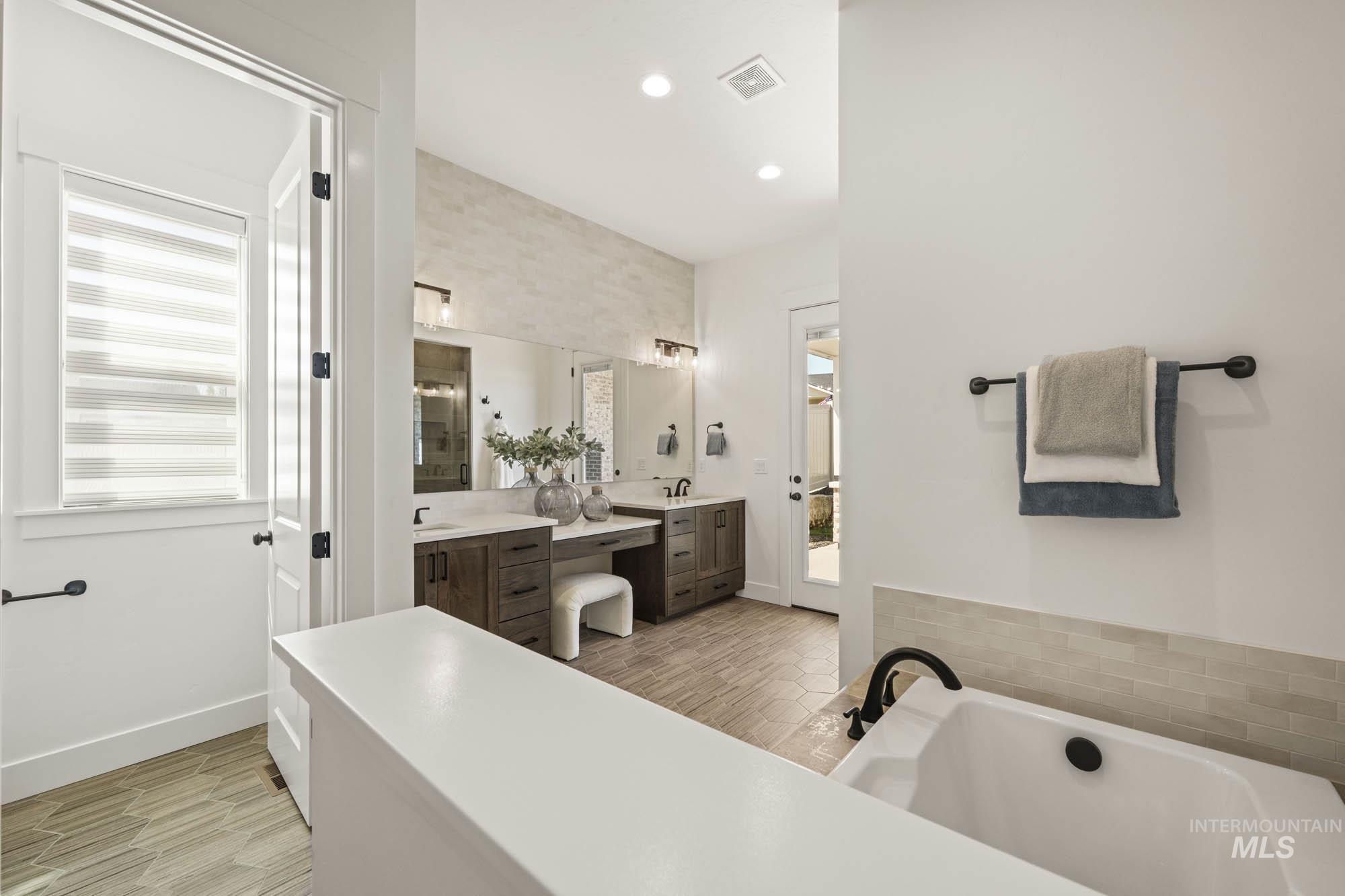 Bathroom with a freestanding bath, double vanity, recessed lighting, and a stall shower