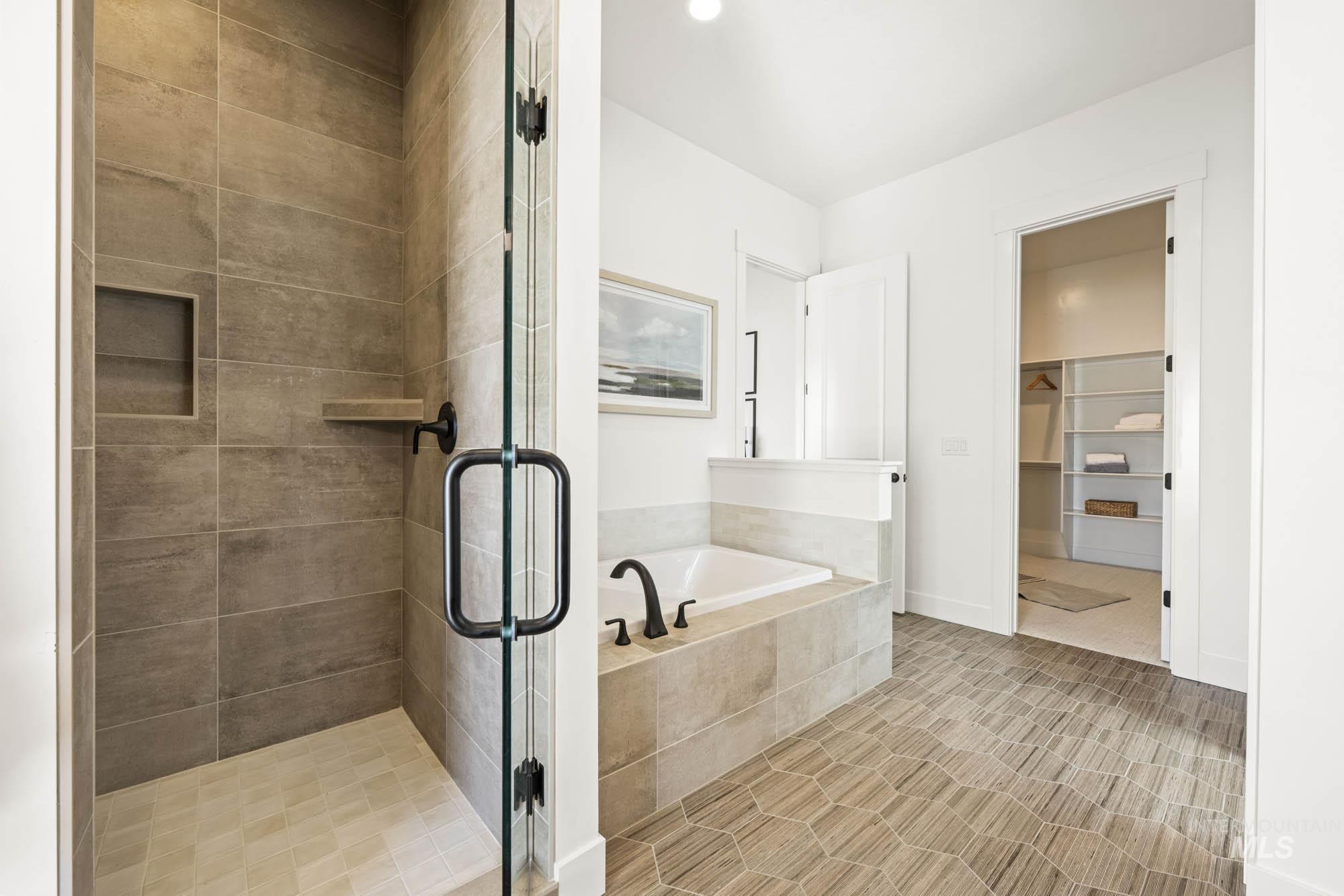 Full bathroom featuring a garden tub, a spacious closet, and a shower stall