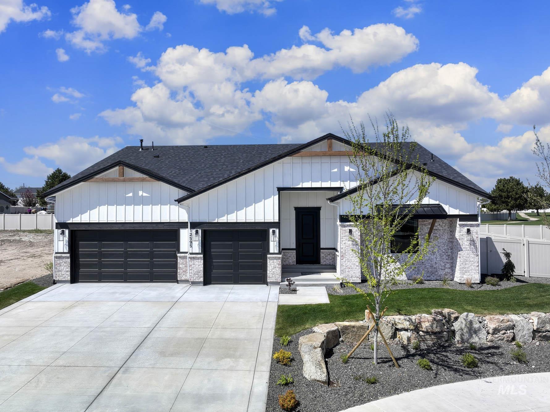 Modern inspired farmhouse featuring board and batten siding, driveway, roof with shingles, and a garage