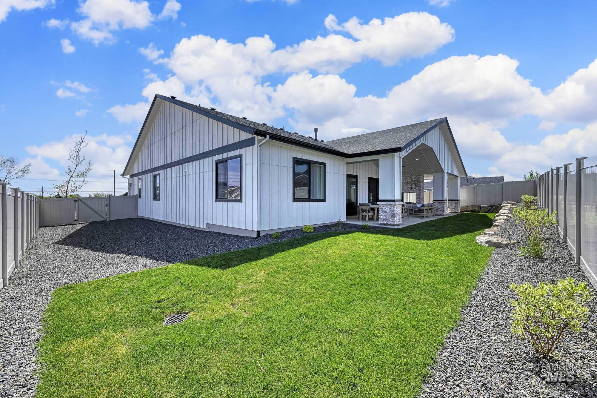 Rear view of property with a fenced backyard, a patio, a gate, stone siding, and a shingled roof