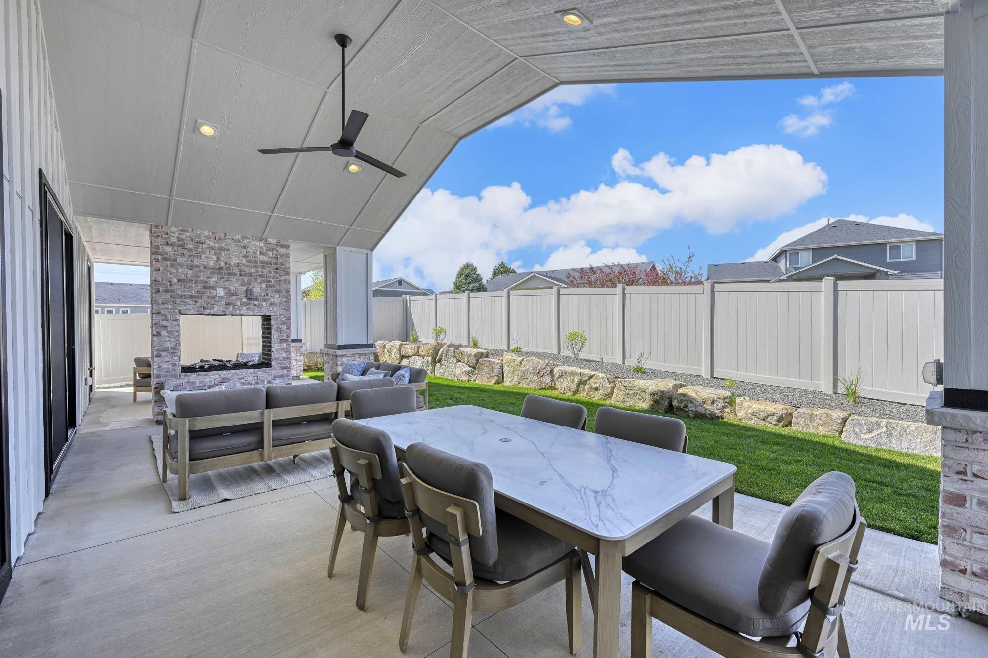 Fenced backyard featuring ceiling fan, a patio, outdoor dining space, and an outdoor hangout area