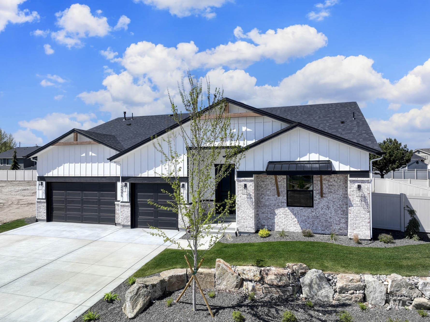 Modern inspired farmhouse featuring brick siding, board and batten siding, concrete driveway, and a shingled roof