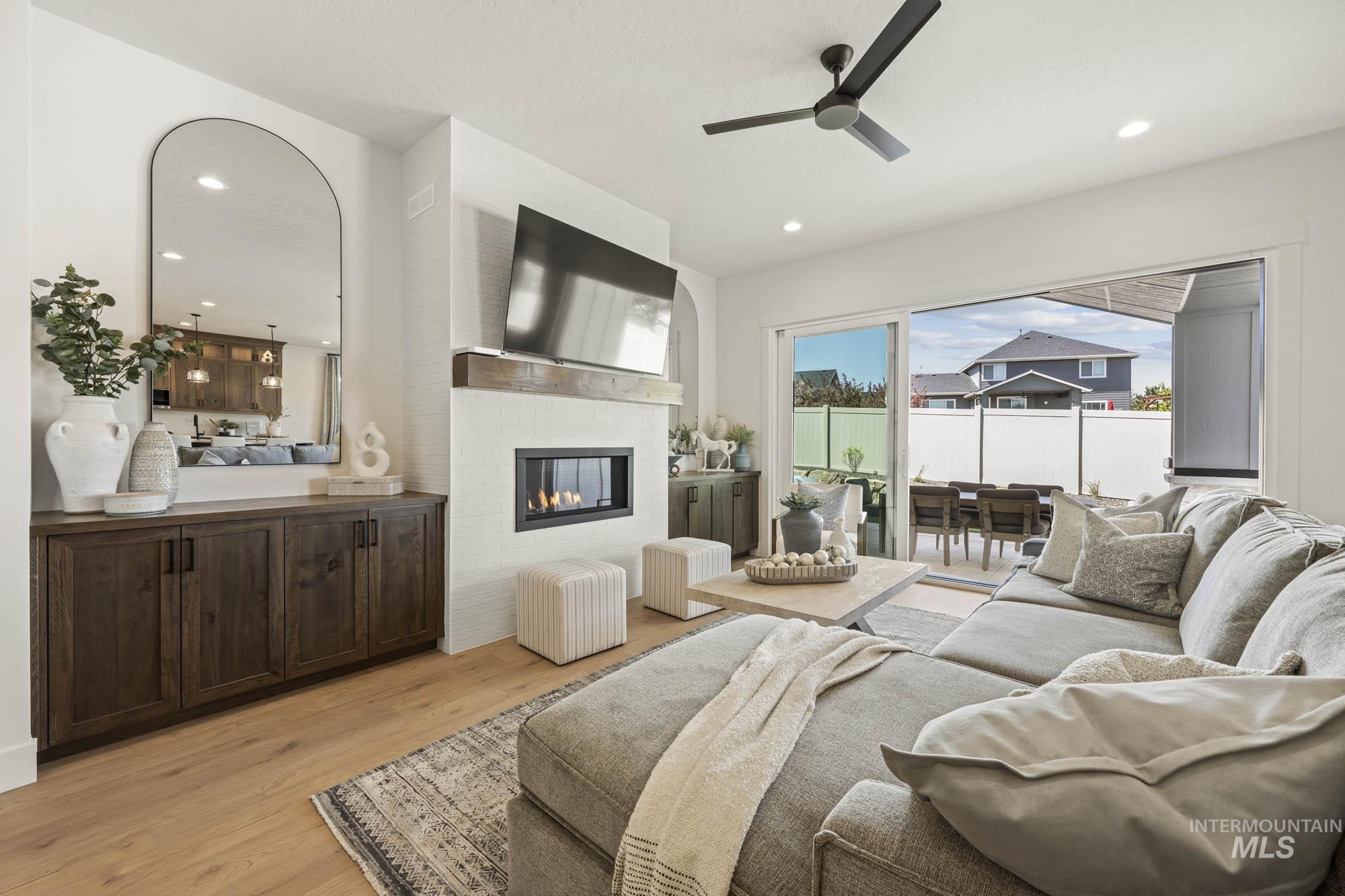 Bedroom with access to exterior, a glass covered fireplace, light wood-style floors, ceiling fan, and recessed lighting