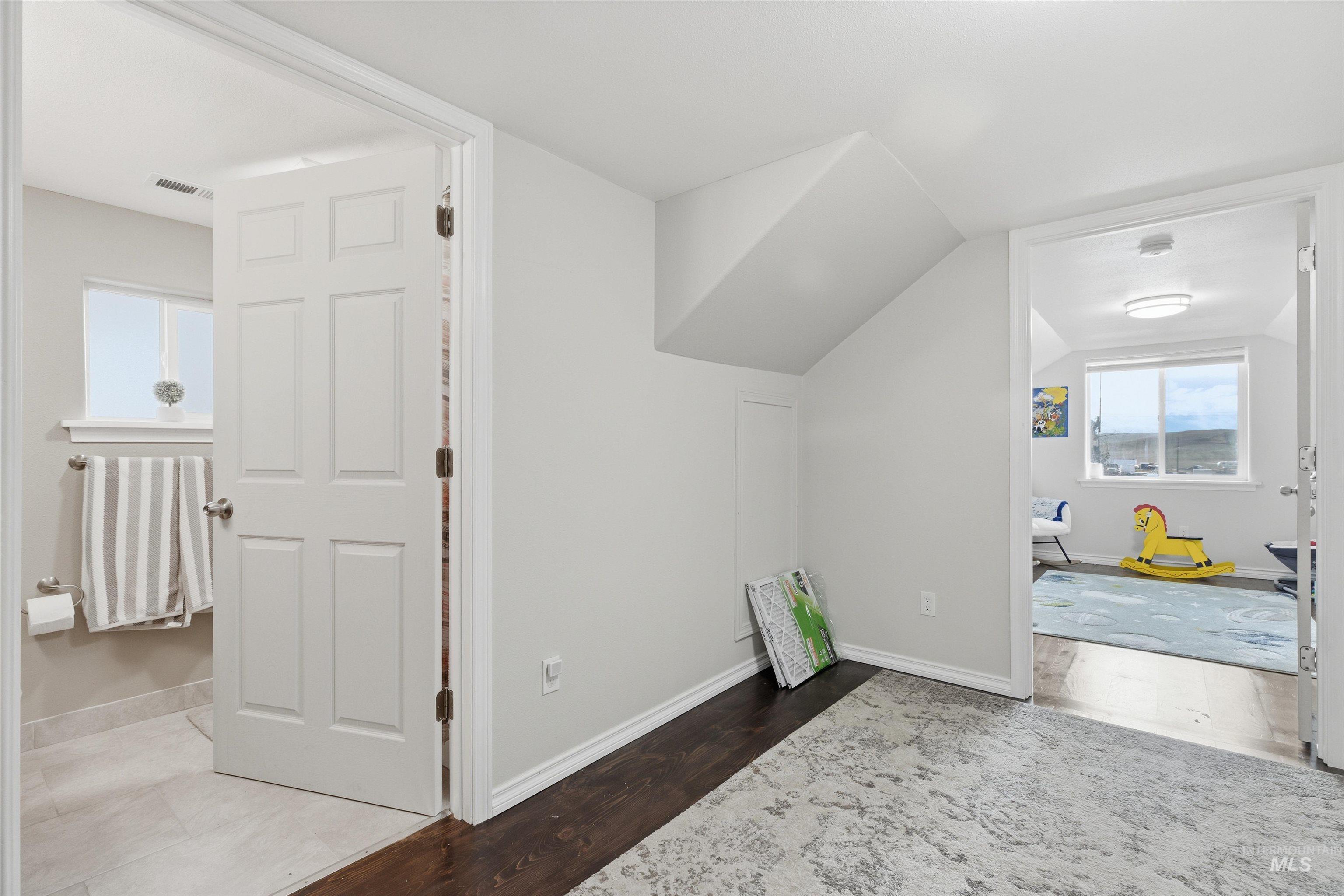 Additional living space with dark wood finished floors and lofted ceiling