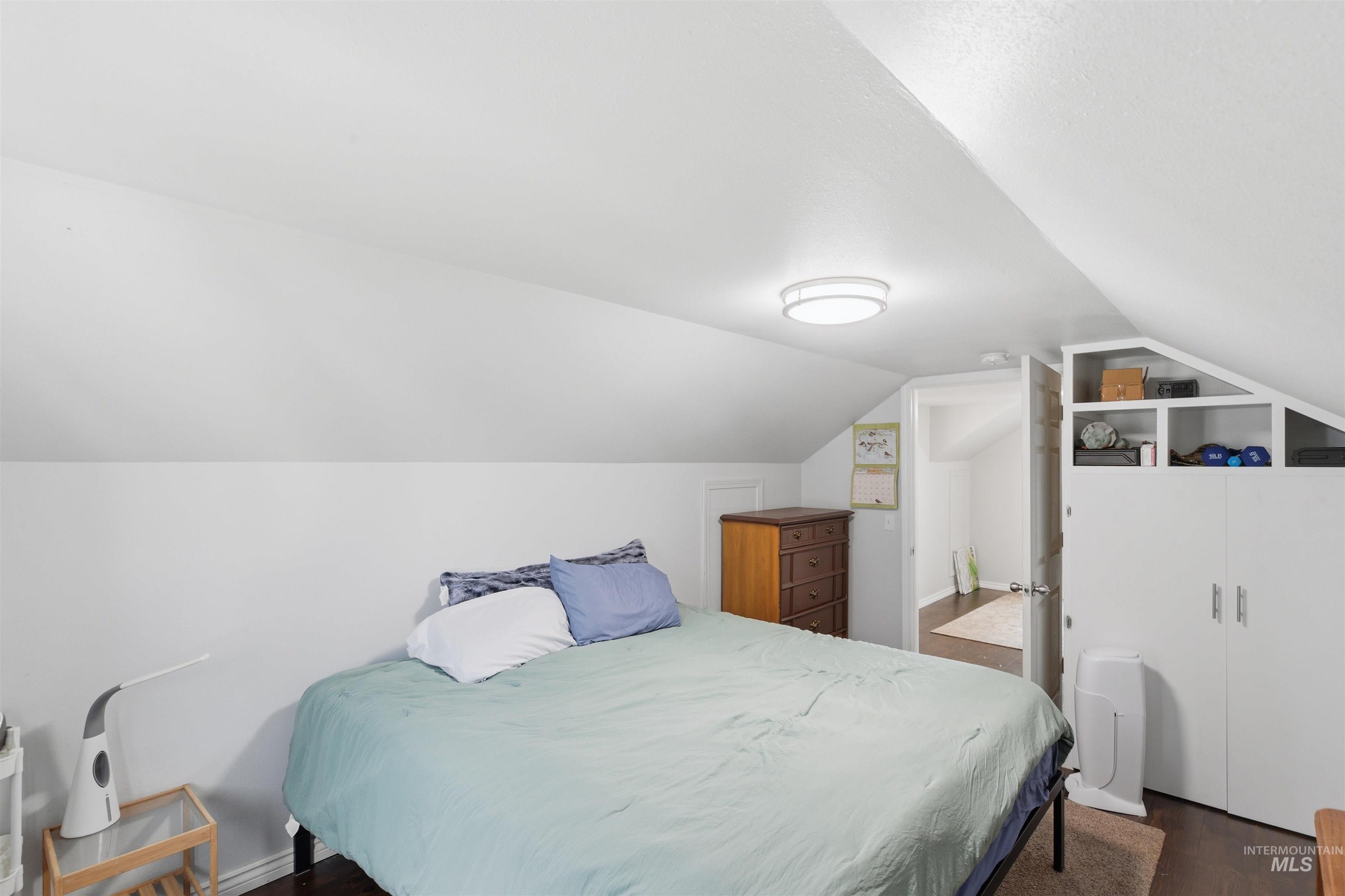 Bedroom with vaulted ceiling and dark wood-style flooring