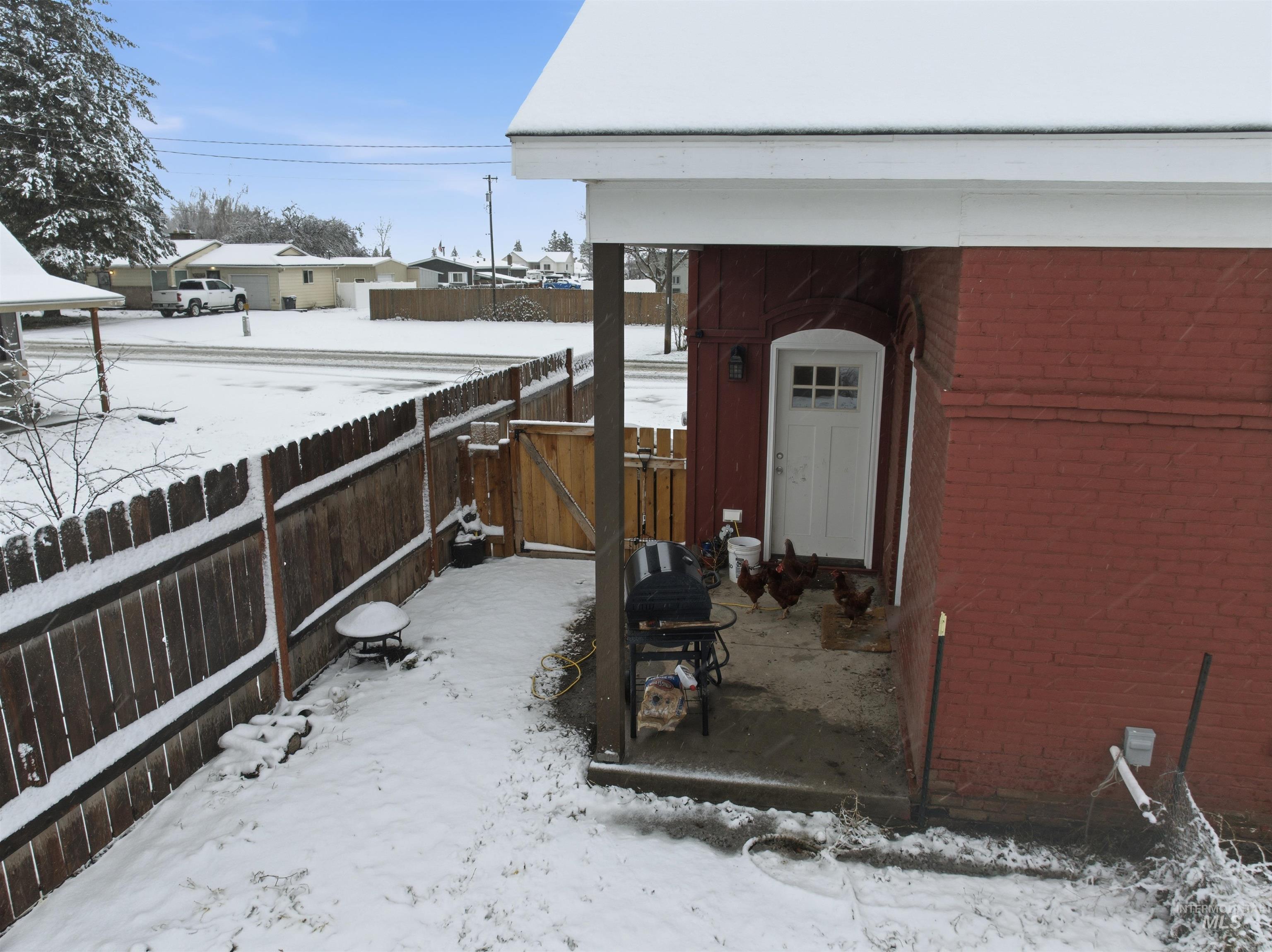 Yard layered in snow featuring a gate