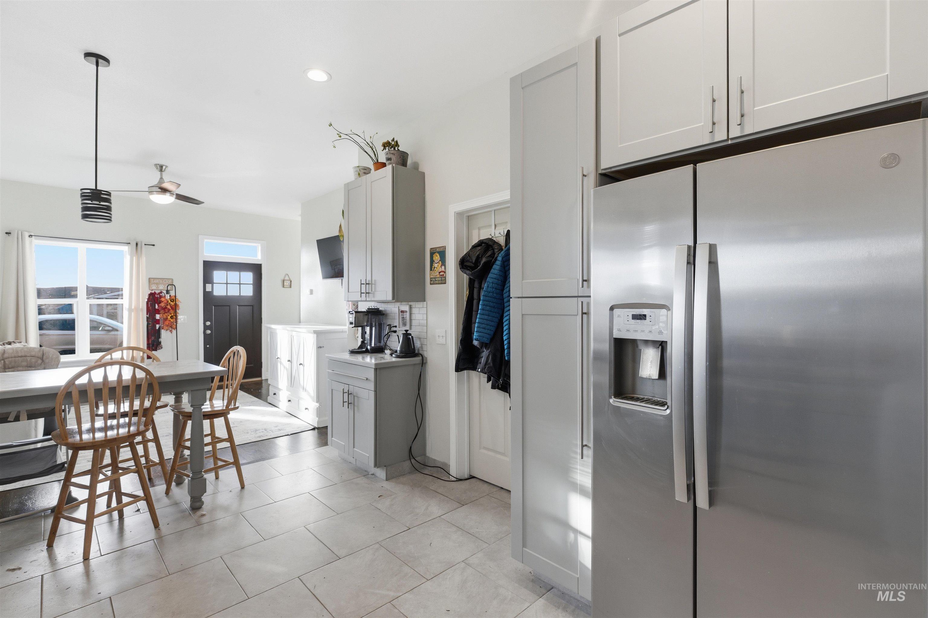 Kitchen with stainless steel refrigerator with ice dispenser, light countertops, decorative light fixtures, ceiling fan, and recessed lighting