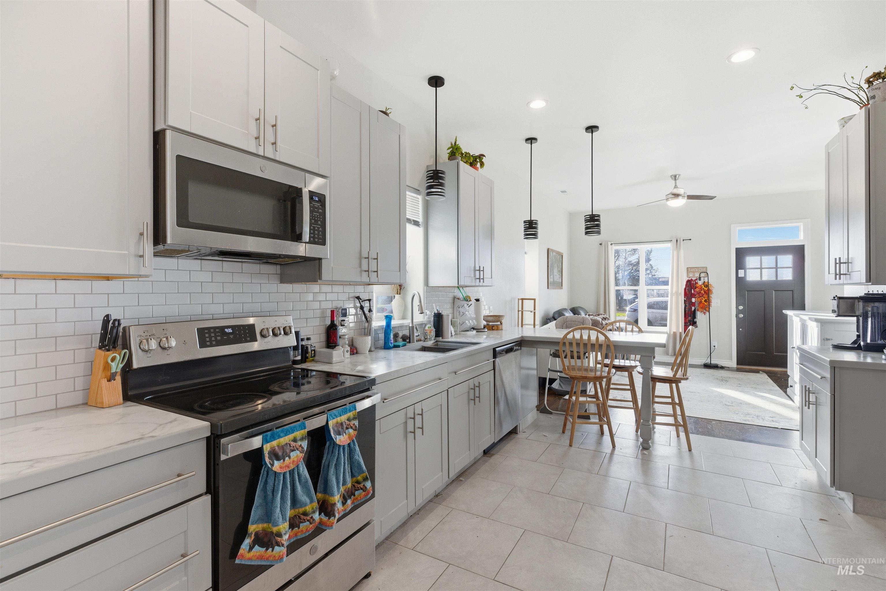 Kitchen featuring appliances with stainless steel finishes, backsplash, recessed lighting, hanging light fixtures, and a ceiling fan