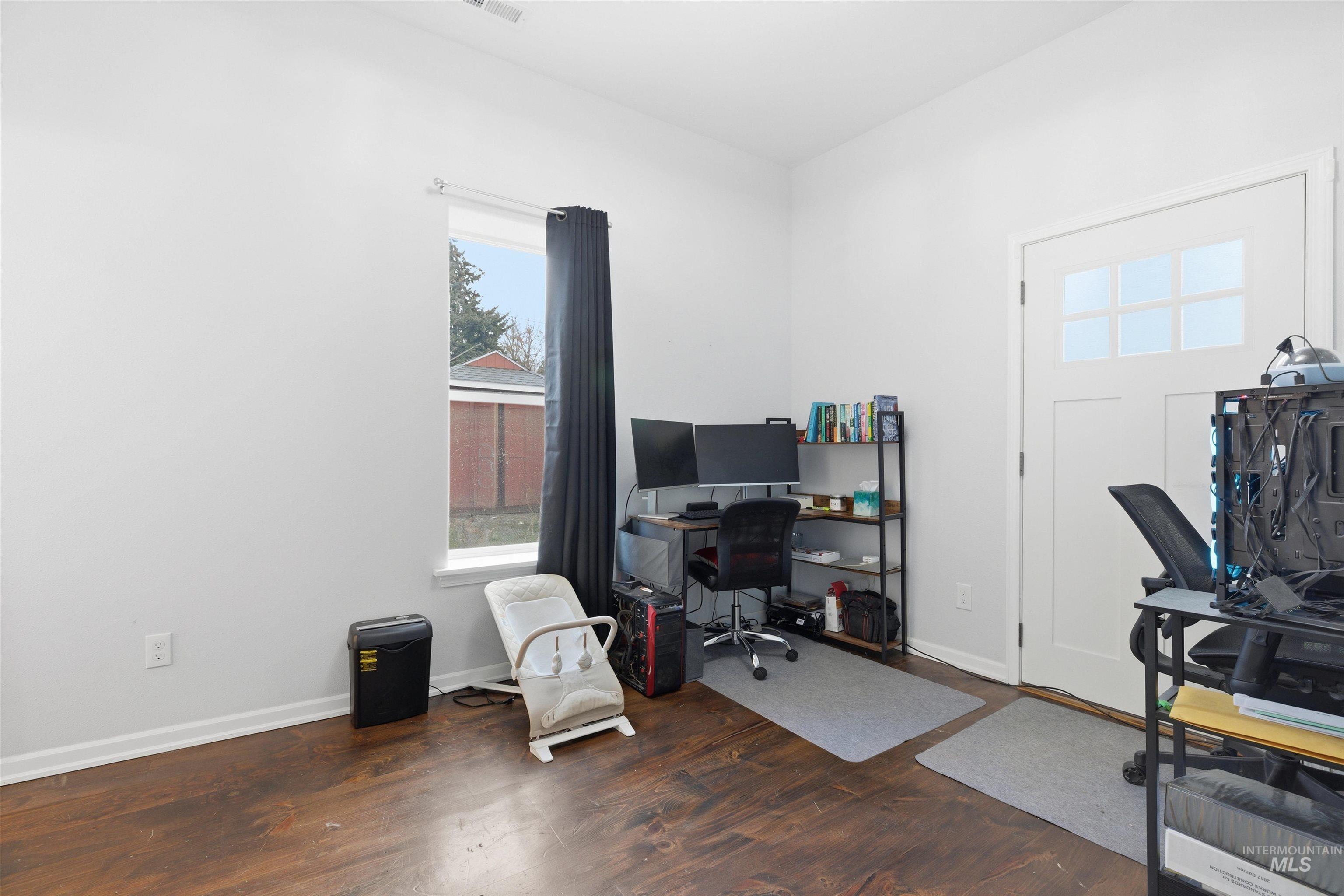 Office with baseboards and dark wood-type flooring