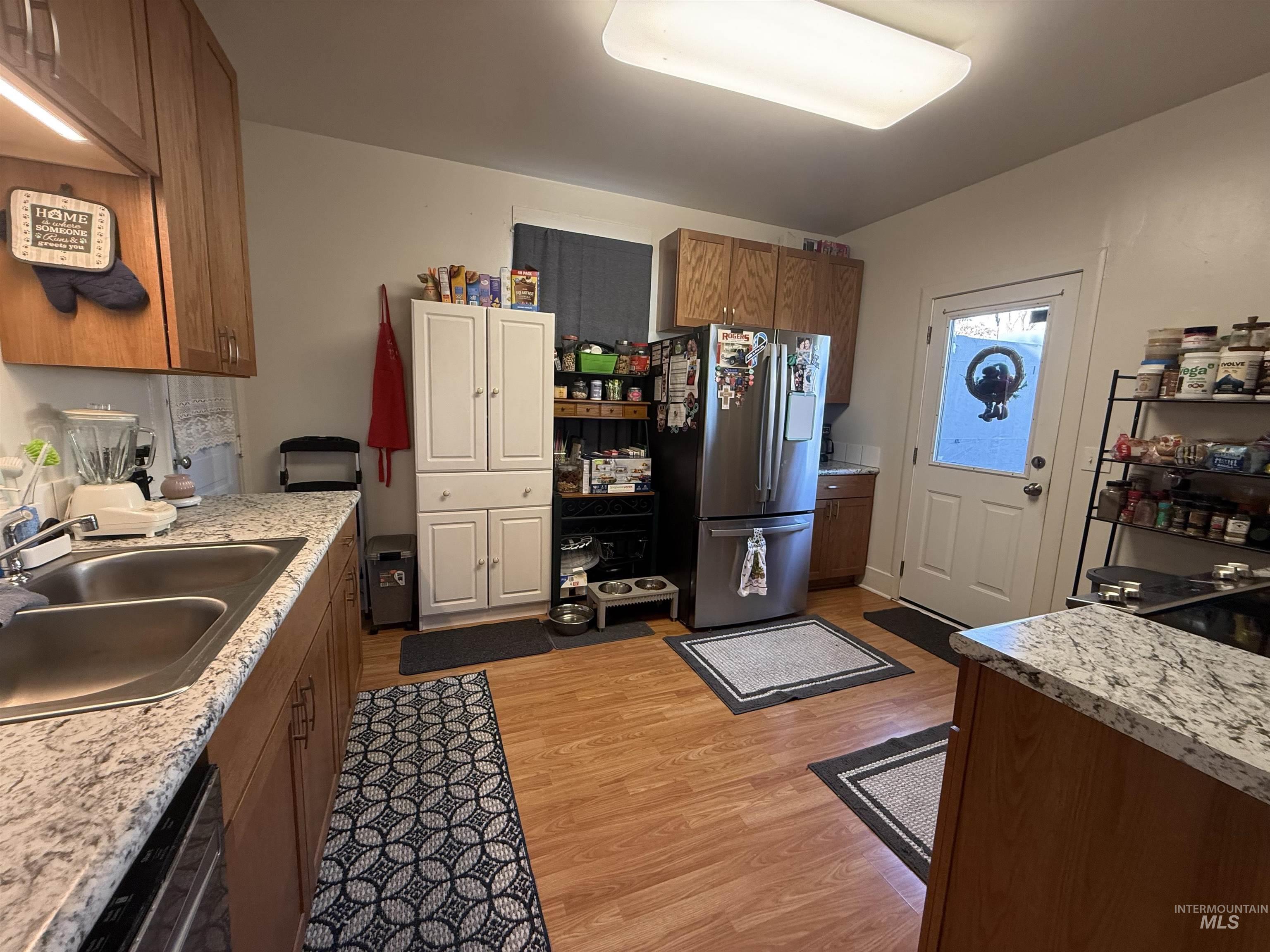 Kitchen featuring brown cabinets, appliances with stainless steel finishes, and light wood-style floors