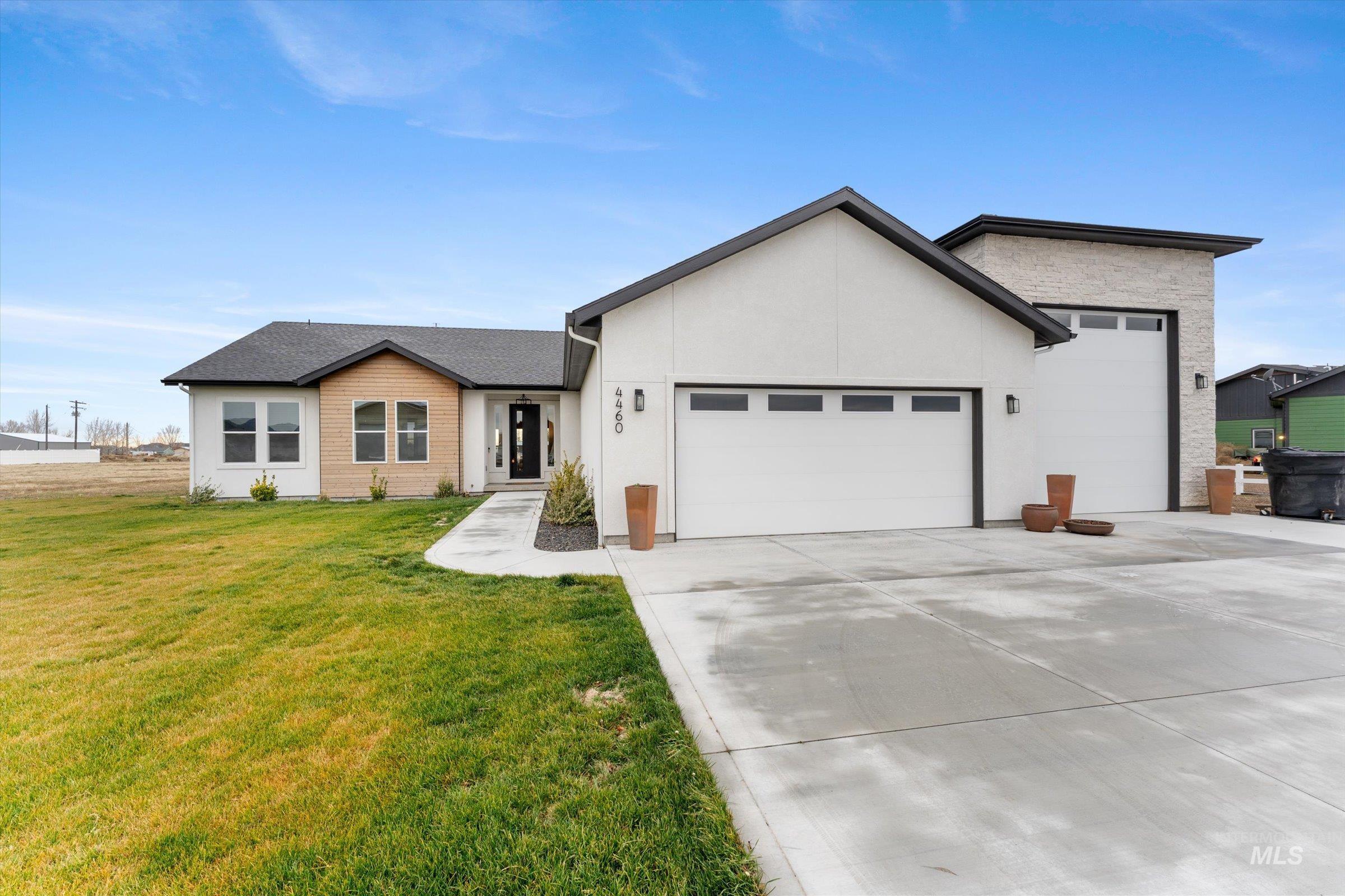 Single story home featuring a garage, a front yard, concrete driveway, stucco siding, and stone siding