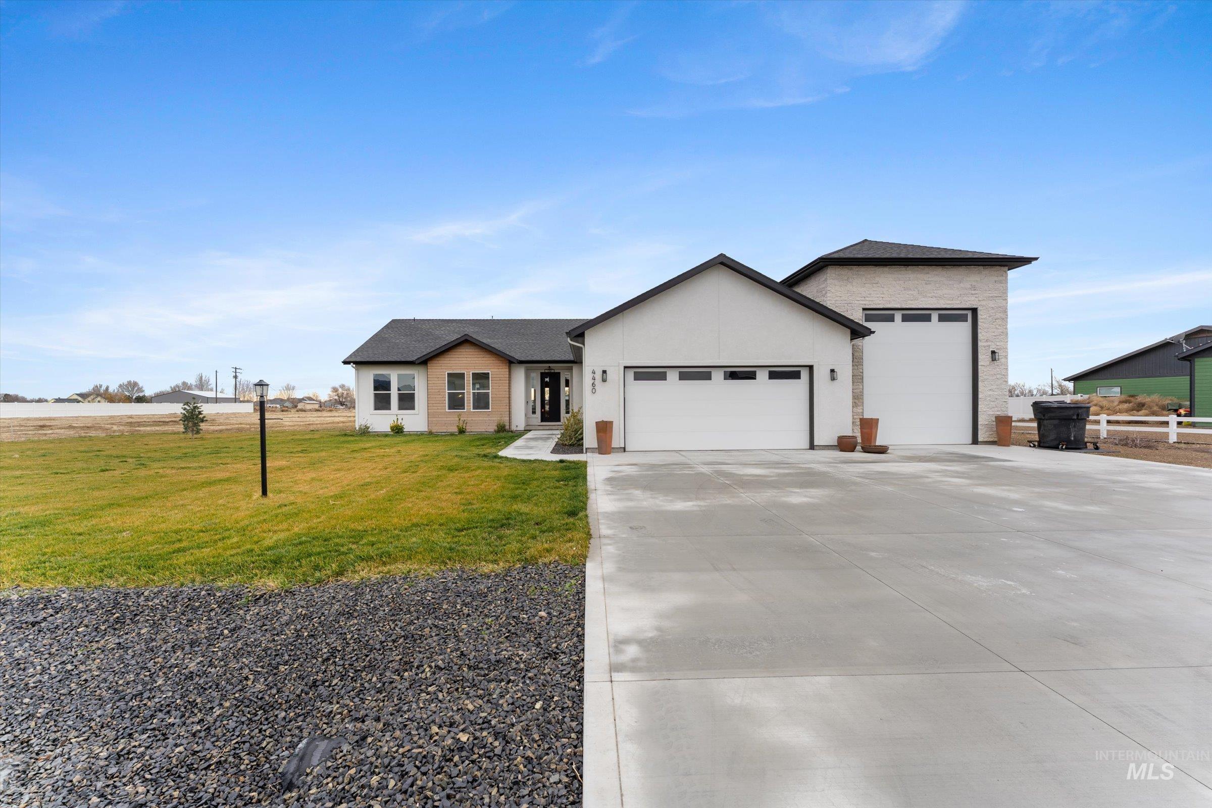 View of front of home with an attached garage, a front lawn, concrete driveway, and wood accent