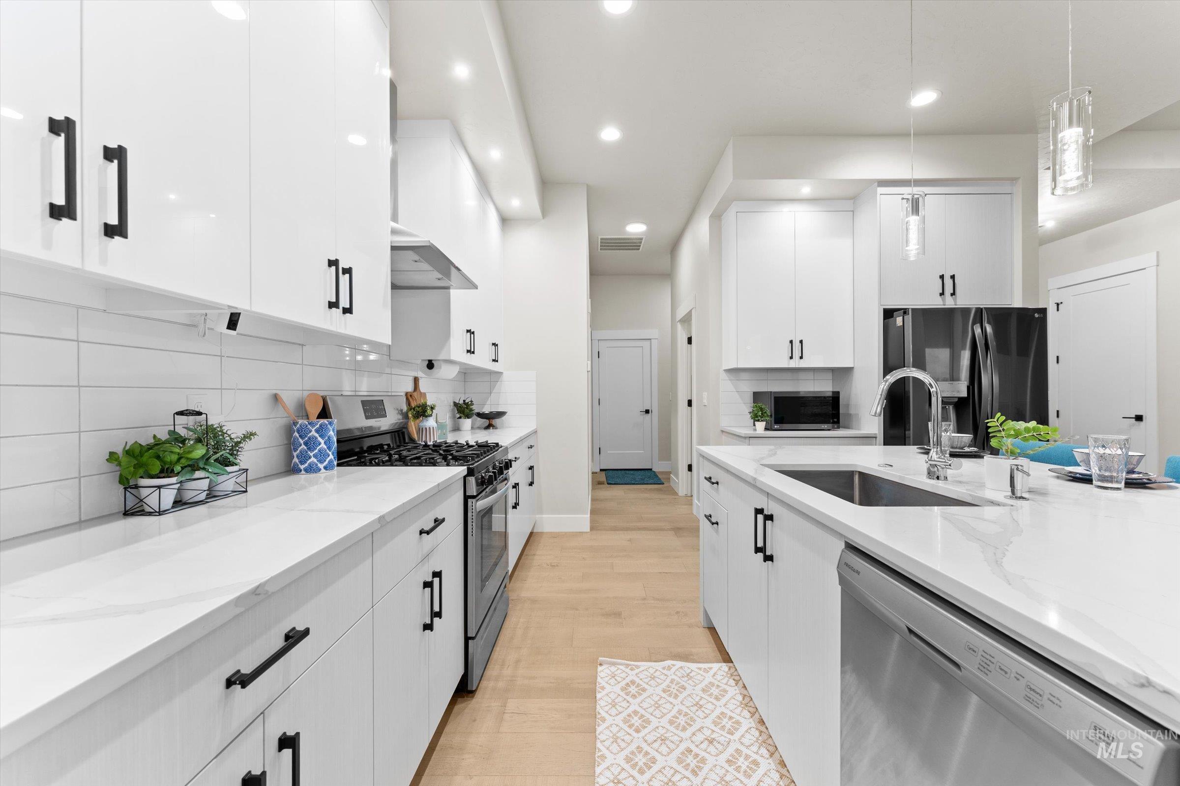 Kitchen with stainless steel appliances, decorative light fixtures, white cabinetry, and recessed lighting