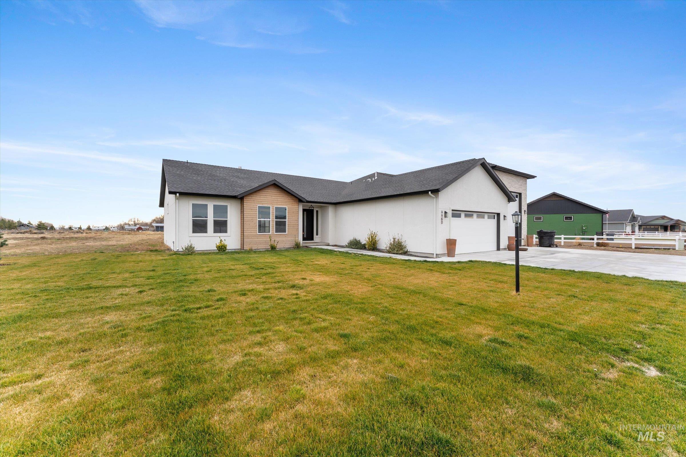View of front featuring a front lawn, concrete driveway, and an attached garage