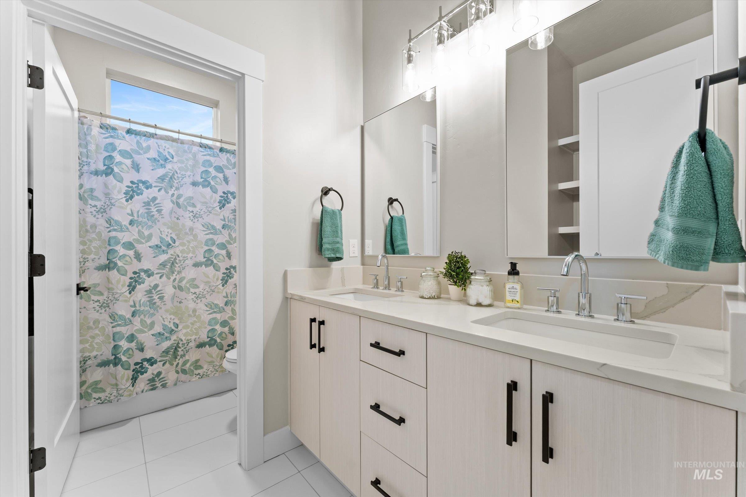 Full bath with double vanity and light tile patterned flooring