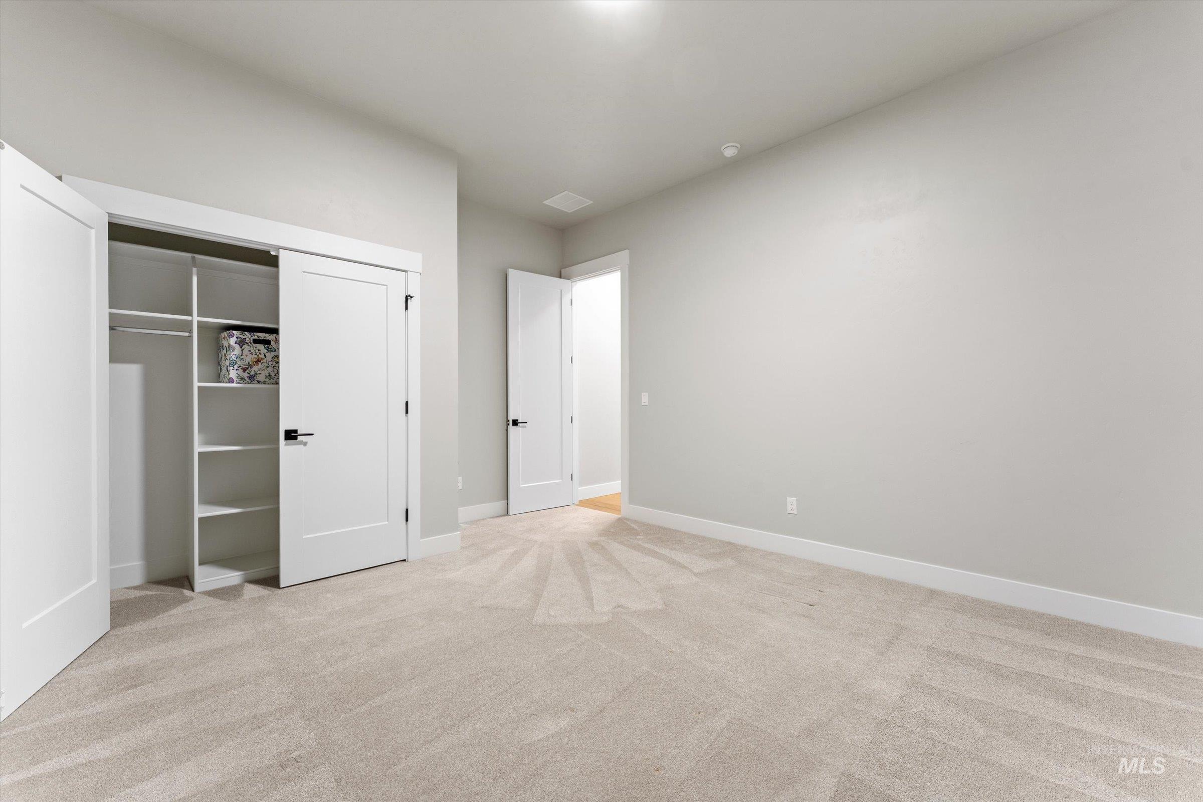 Unfurnished bedroom featuring light carpet and a closet