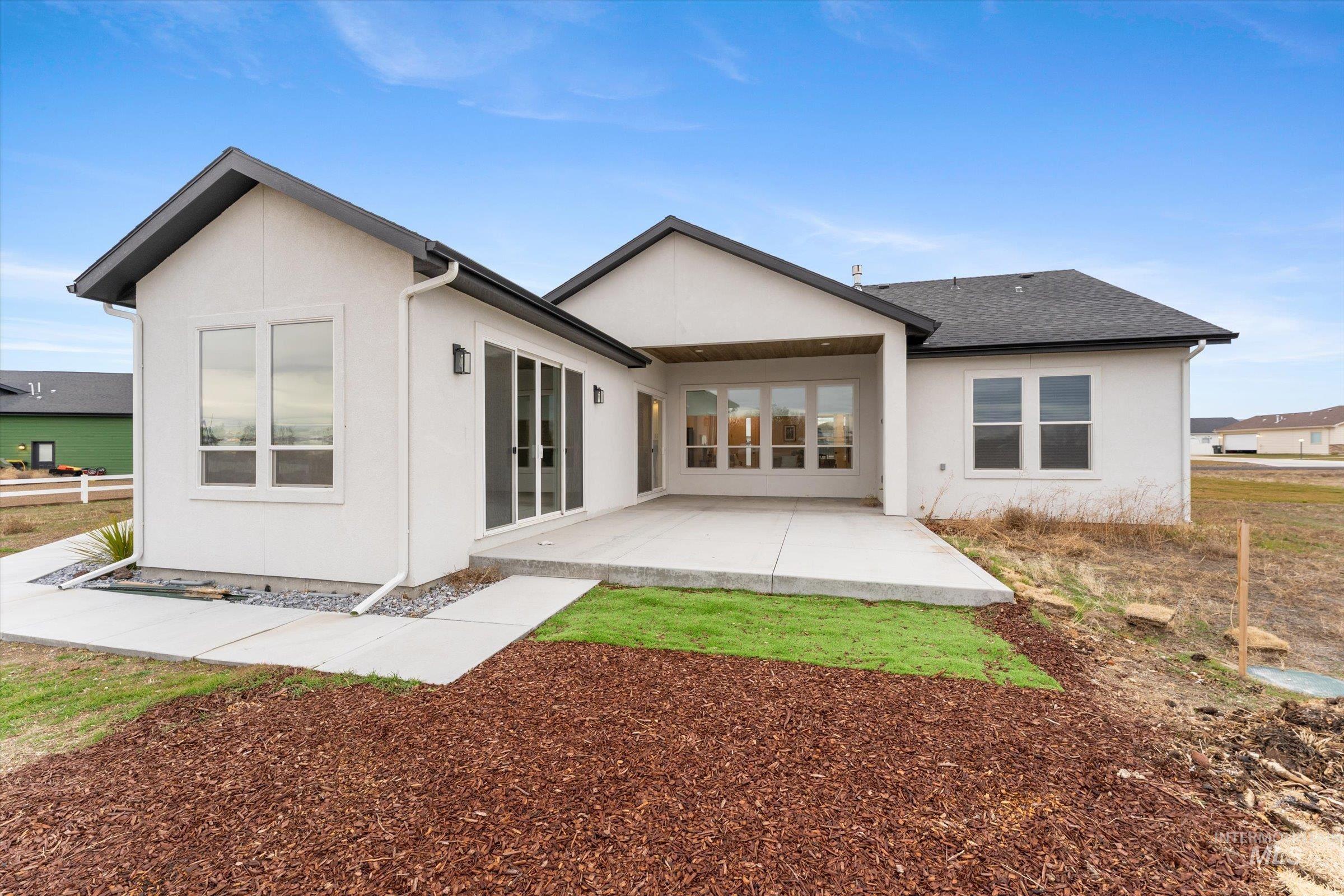 Back of house with a patio, stucco siding, and roof with shingles