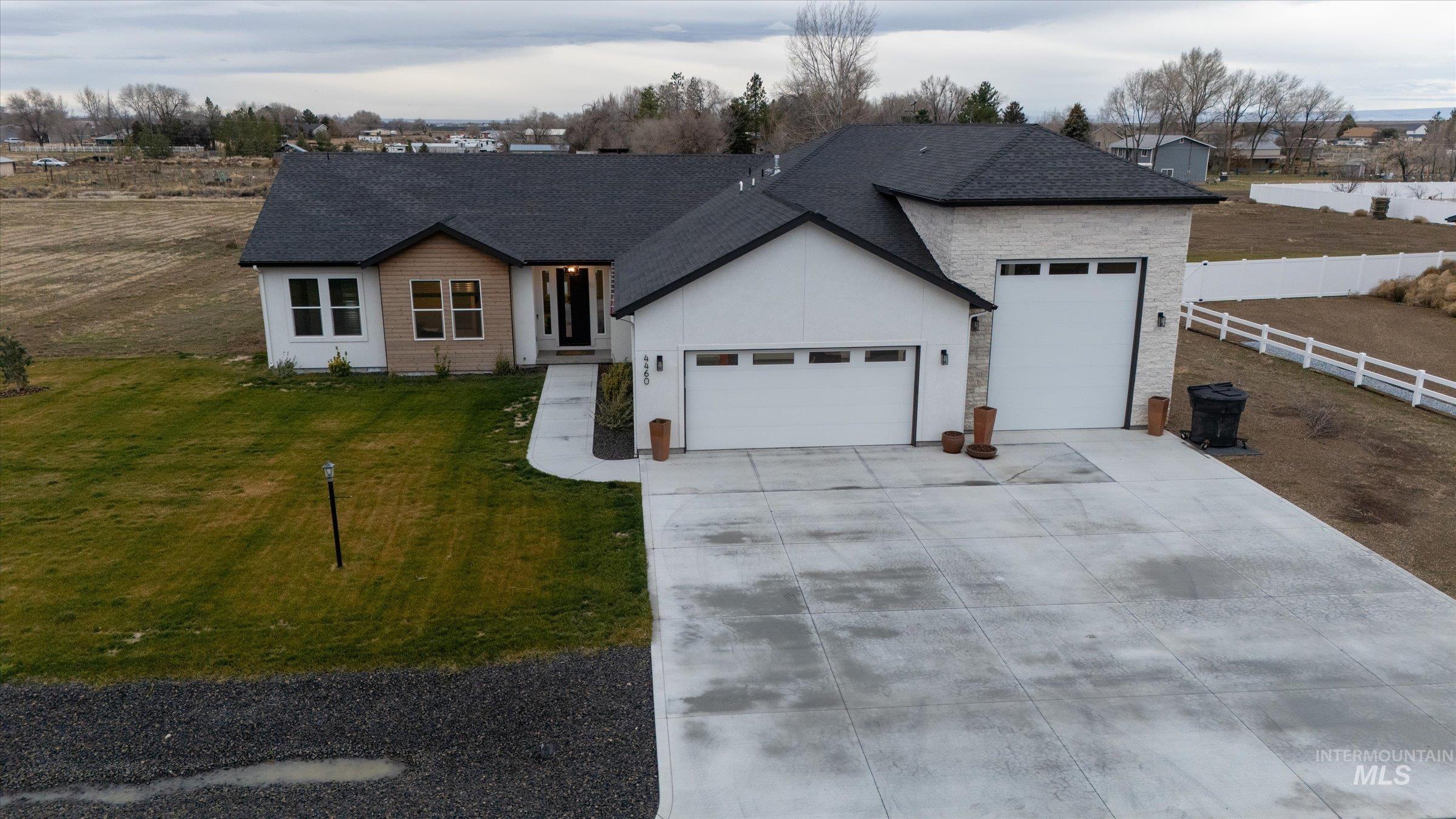 Ranch-style home featuring an attached garage, driveway, roof with shingles, and stucco siding