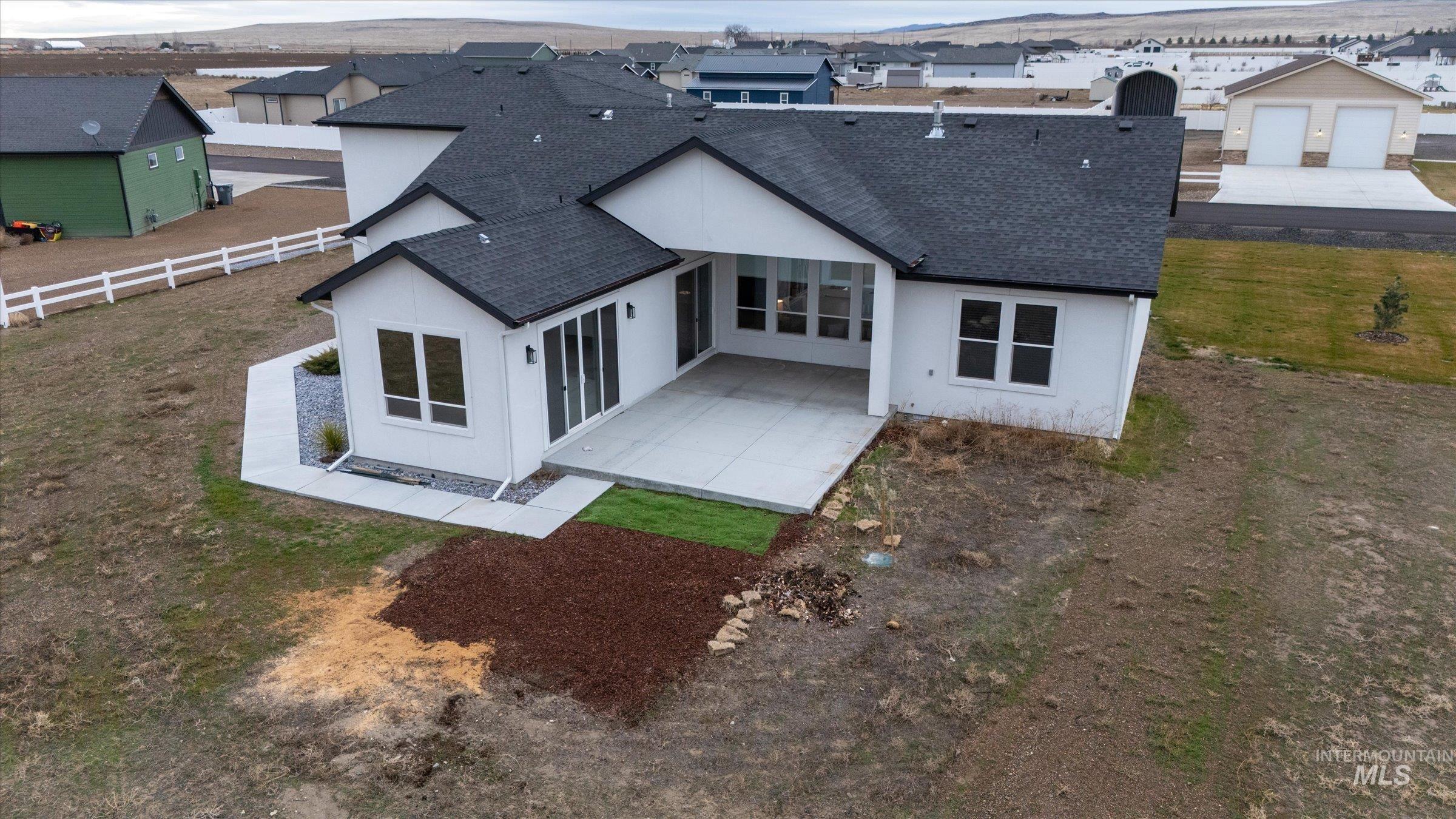 Rear view of property with a shingled roof, a patio, and stucco siding