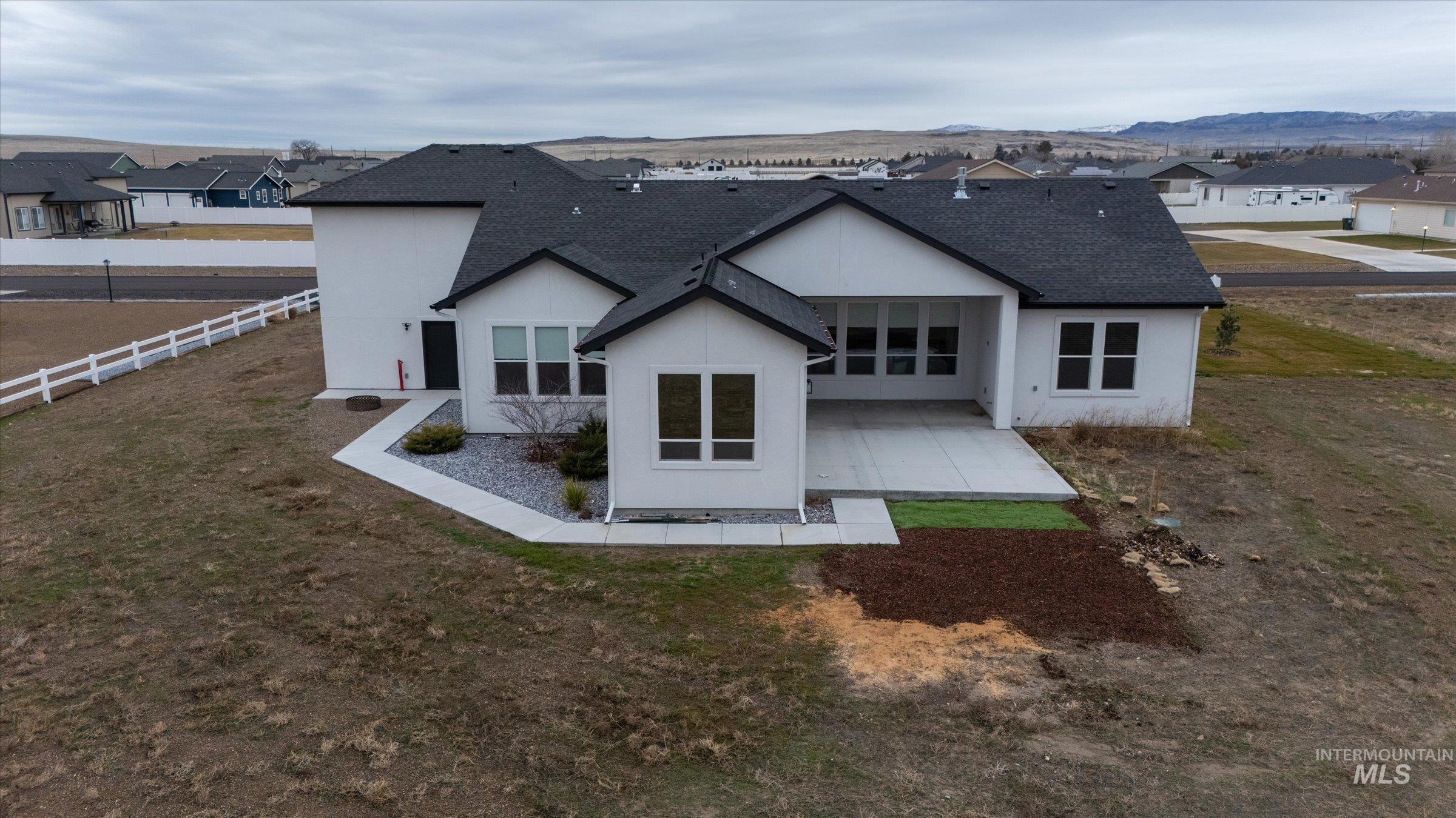 Back of property with a patio area, a shingled roof, stucco siding, and a residential view