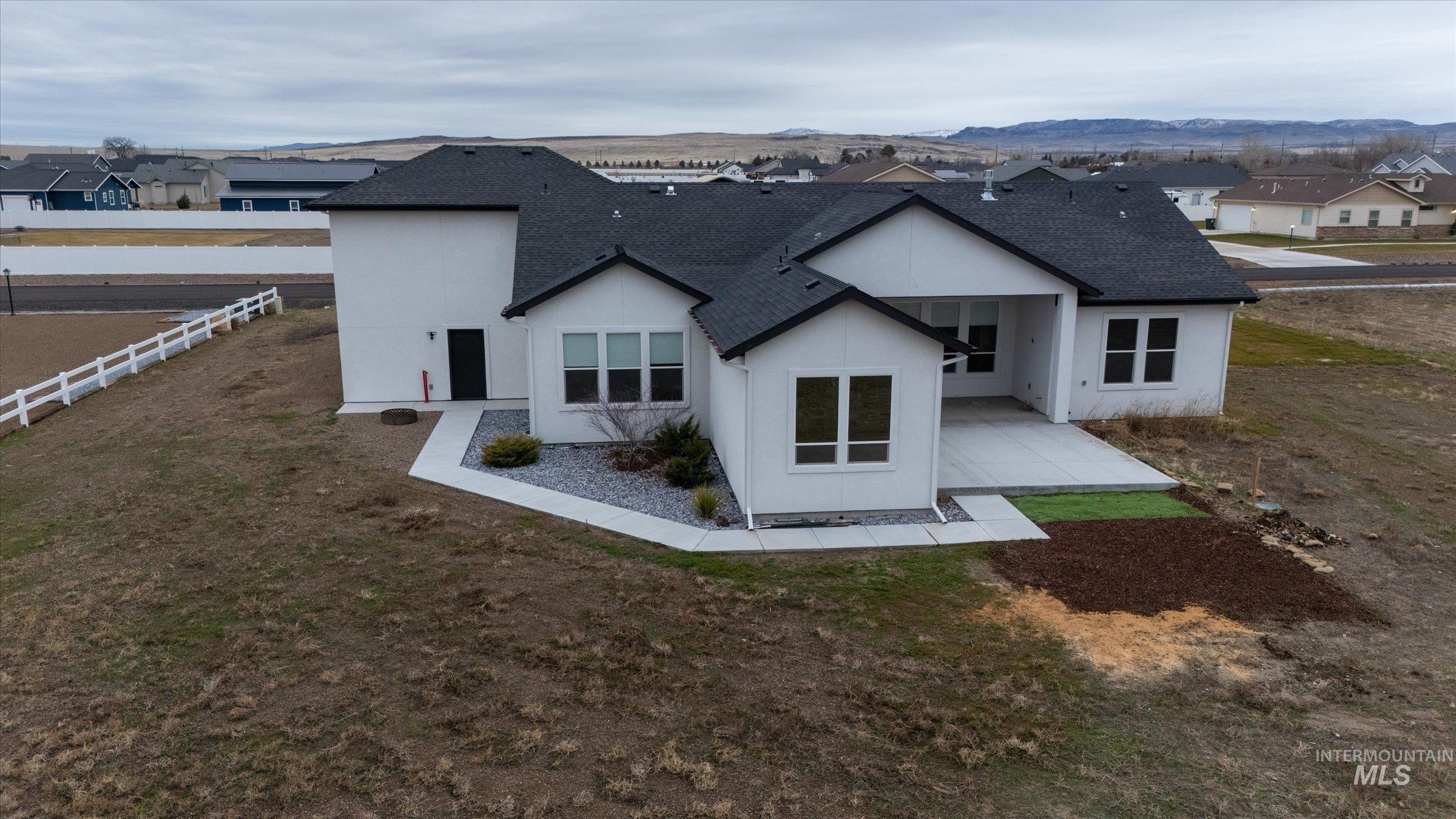 Rear view of house with roof with shingles, a patio area, a residential view, stucco siding, and a mountain view