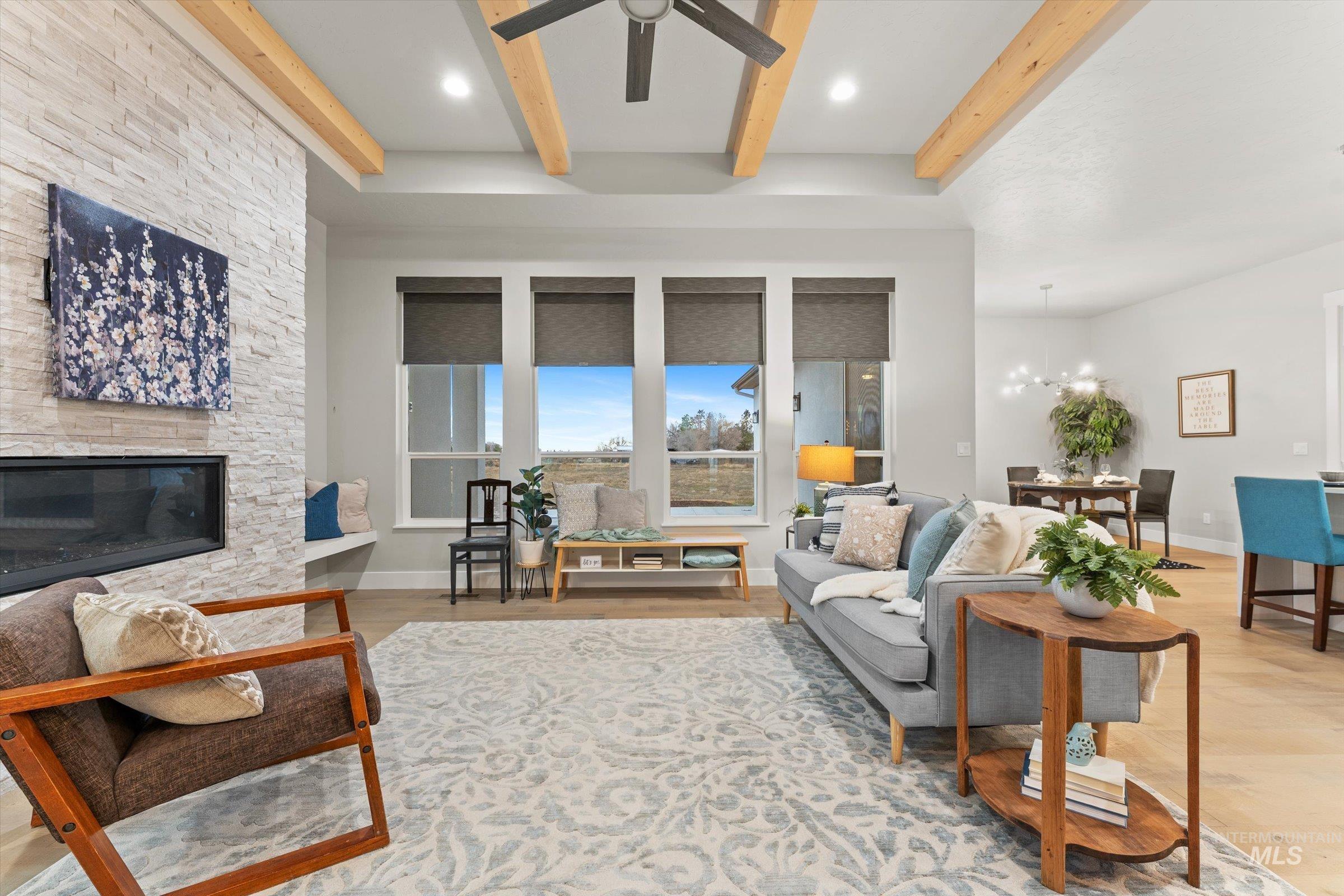 Living area featuring a stone fireplace, recessed lighting, beamed ceiling, light wood-style floors, and a chandelier