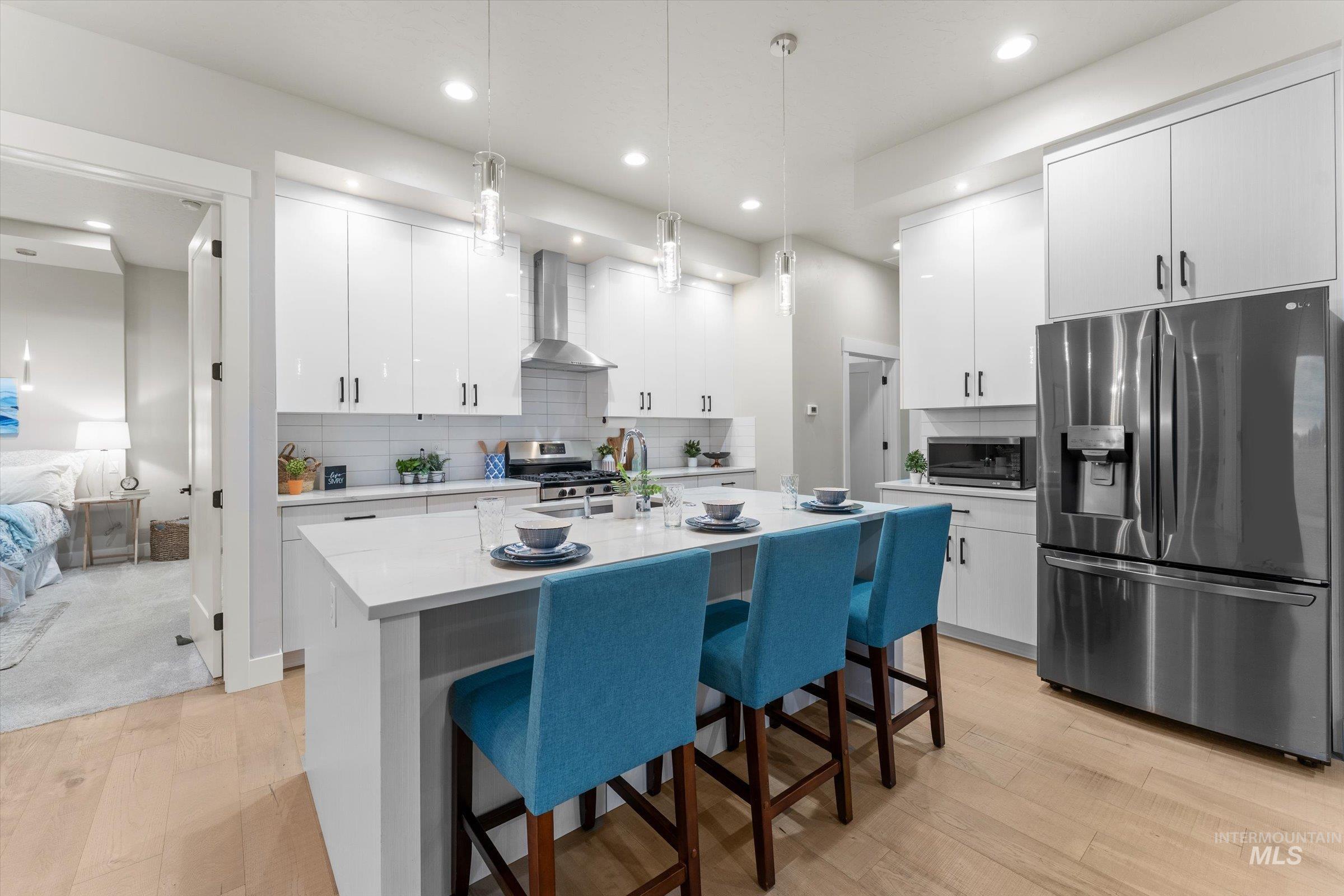 Kitchen with appliances with stainless steel finishes, a kitchen breakfast bar, white cabinets, pendant lighting, and recessed lighting