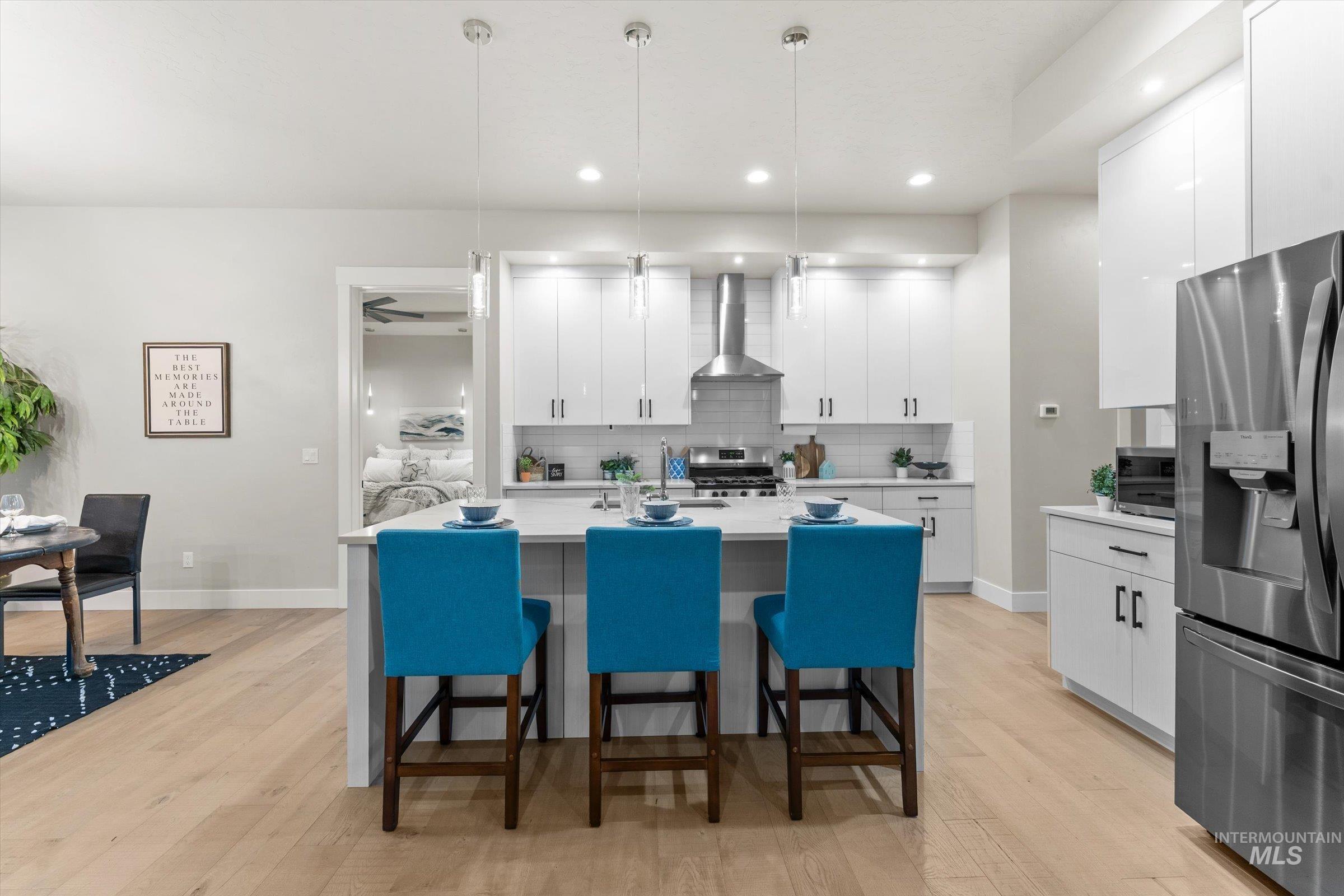 Kitchen featuring stainless steel appliances, a breakfast bar area, pendant lighting, white cabinets, and a kitchen island with sink