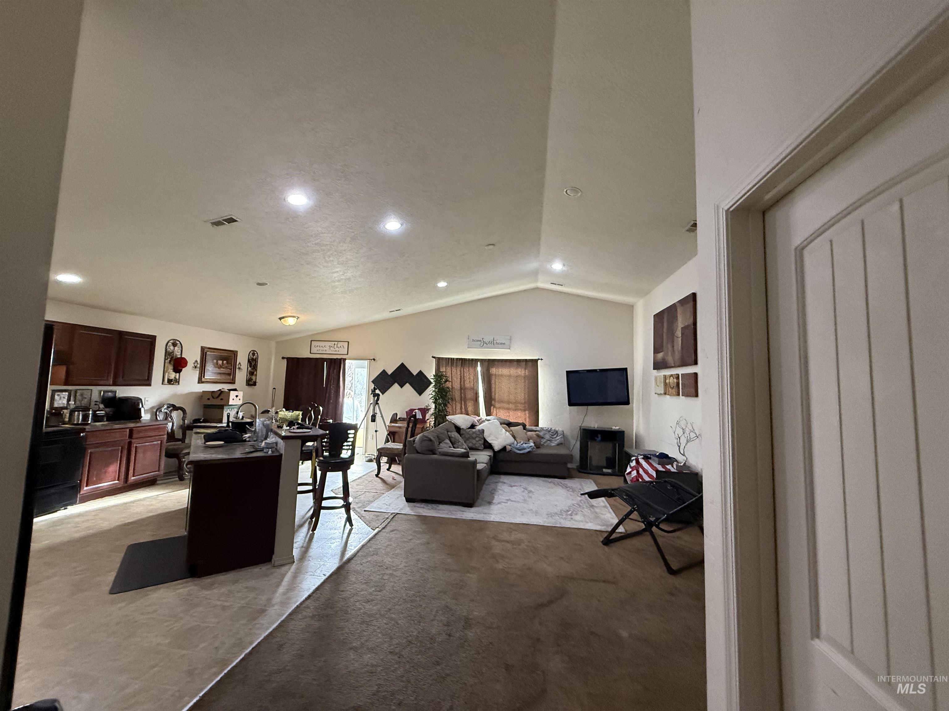Living area featuring lofted ceiling, recessed lighting, and light colored carpet