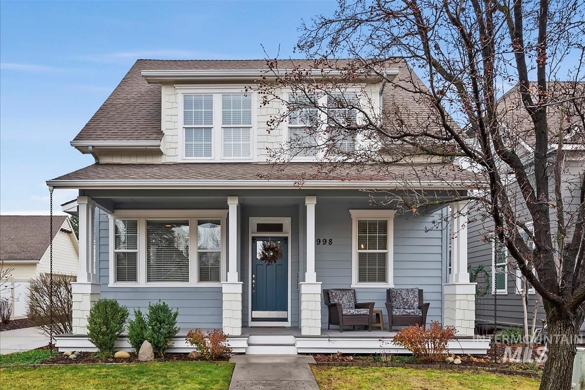 View of front of home with a shingled roof, a porch, and a front lawn