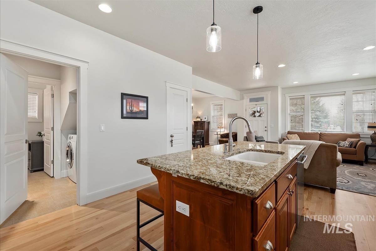 Kitchen featuring healthy amount of natural light, light stone counters, decorative light fixtures, light wood-style floors, and recessed lighting