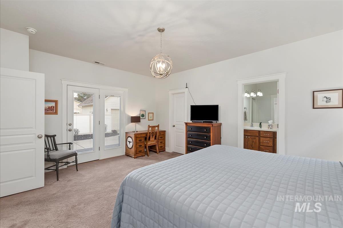 Bedroom featuring light colored carpet, access to outside, and a chandelier