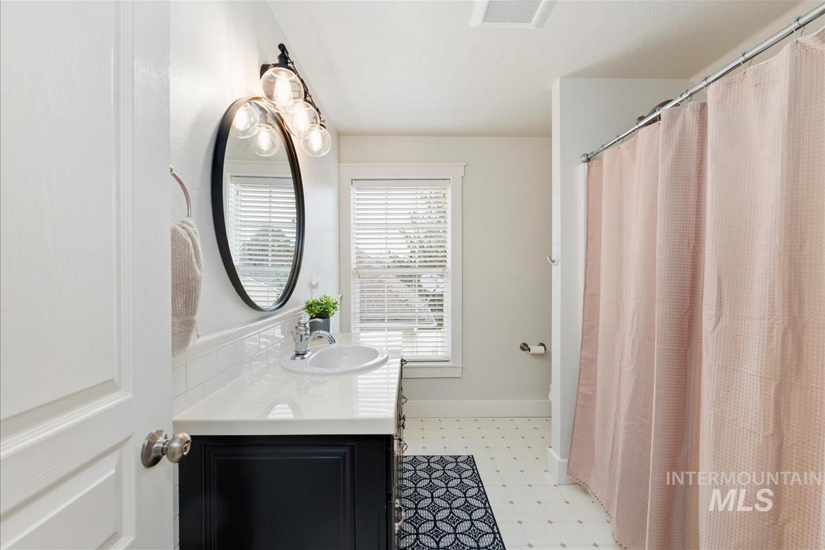 Full bathroom featuring light flooring, vanity, and a shower with curtain