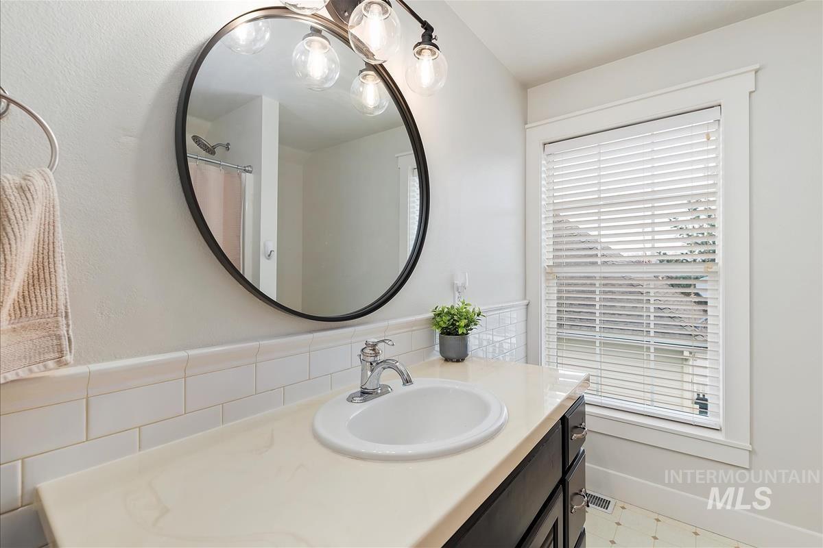 Full bathroom with vanity, curtained shower, and light floors