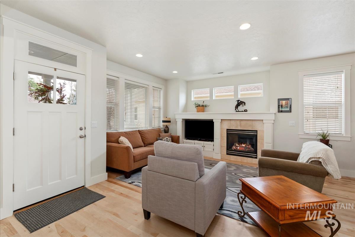 Living room featuring a tiled fireplace, recessed lighting, and light wood-type flooring