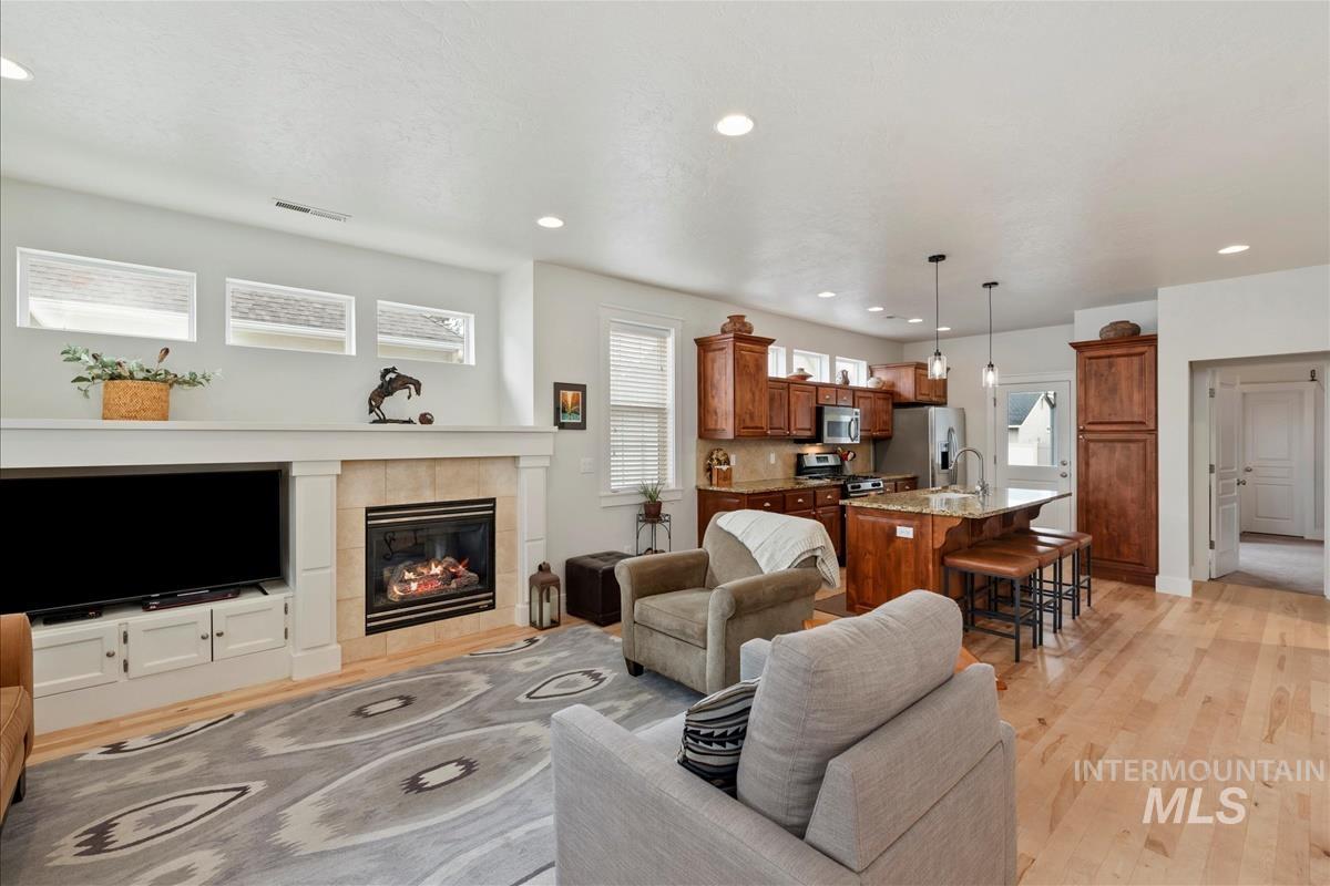 Living room with a fireplace, light wood-style flooring, and recessed lighting