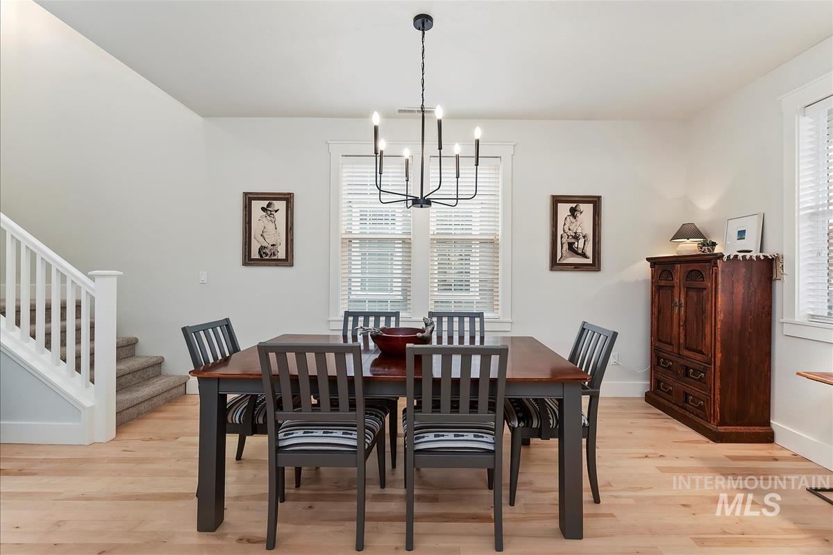Dining room with stairs, light wood-style floors, and a chandelier