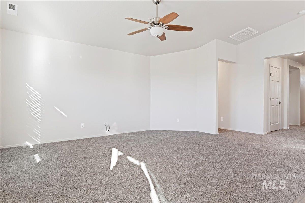 Spare room featuring light colored carpet, ceiling fan, and lofted ceiling