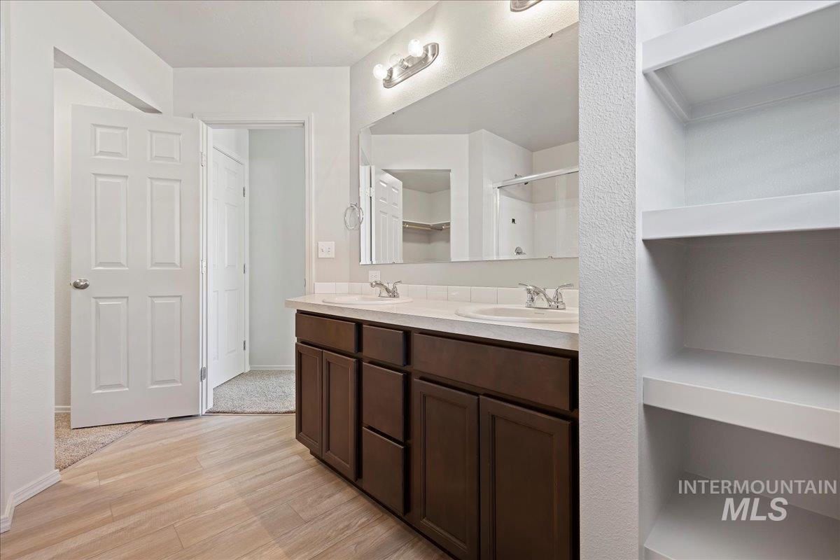 Bathroom with double vanity, light wood-style flooring, and a shower