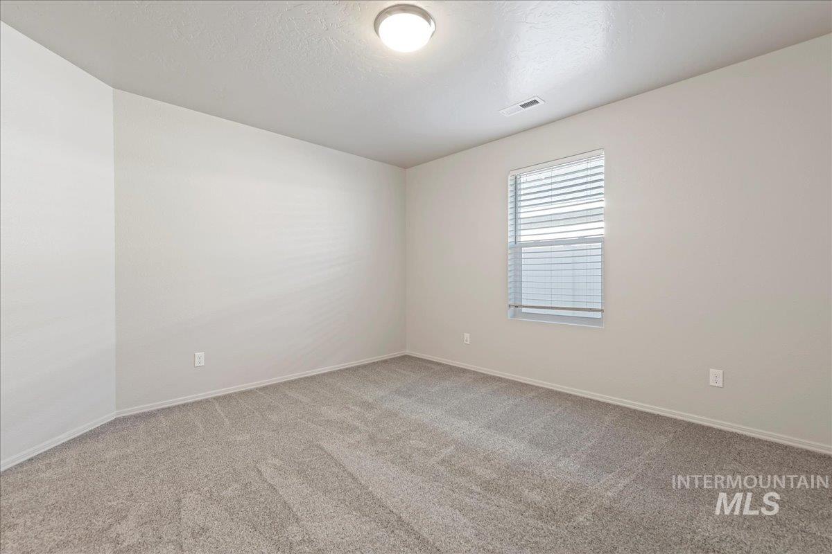 Empty room featuring light carpet and a textured ceiling