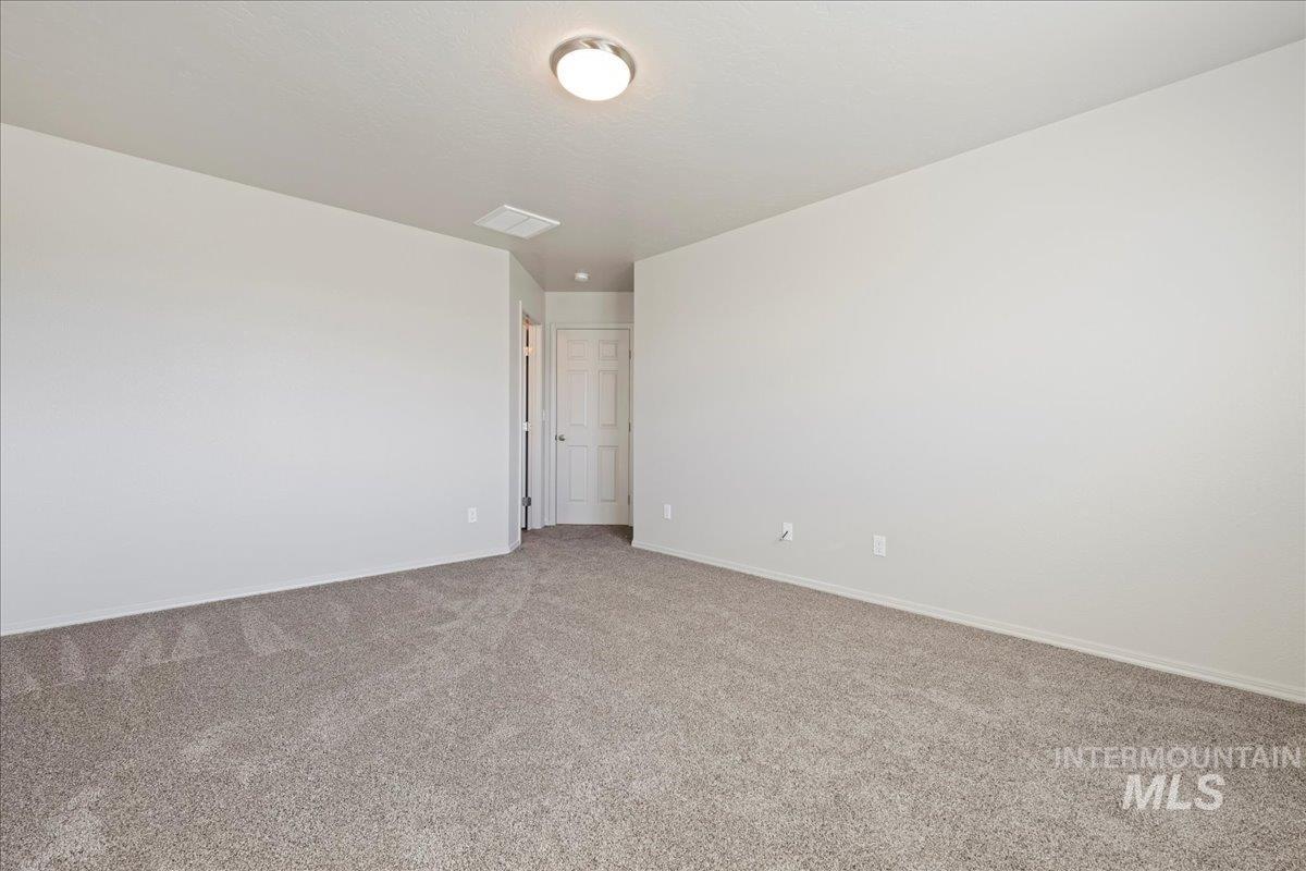 Spare room featuring carpet flooring and baseboards