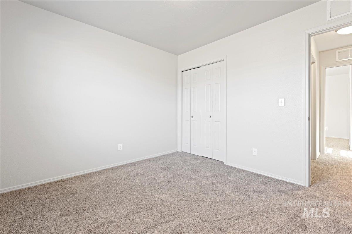 Unfurnished bedroom with light colored carpet and a closet