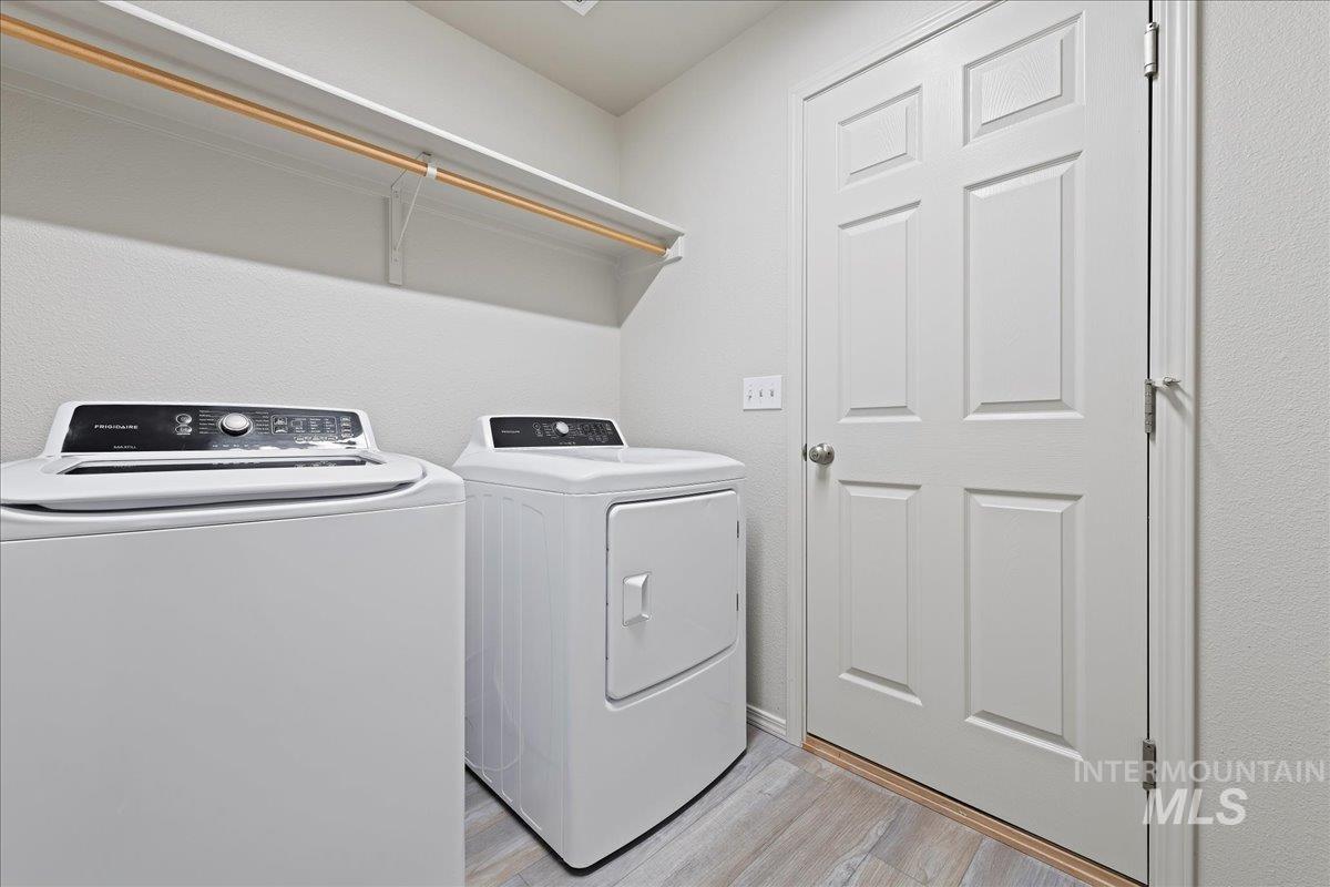 Laundry area with light wood-type flooring and washing machine and clothes dryer