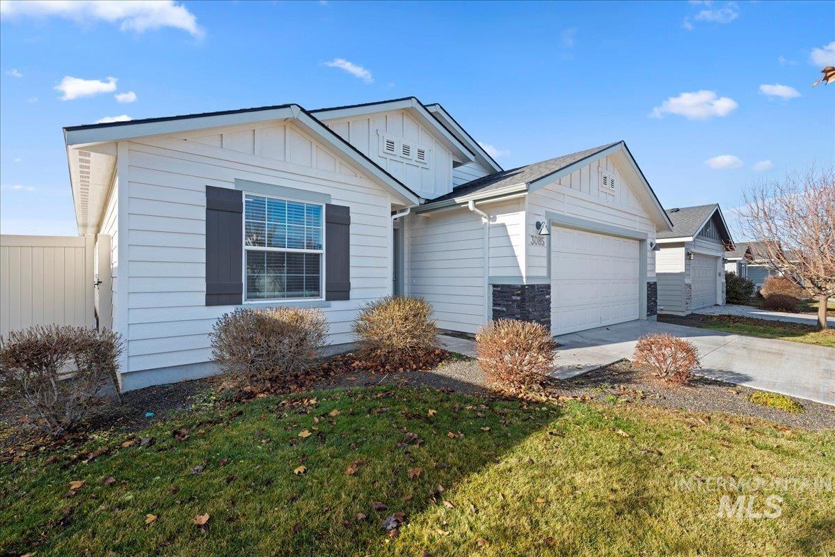 View of front of property with board and batten siding, driveway, a front yard, and a garage