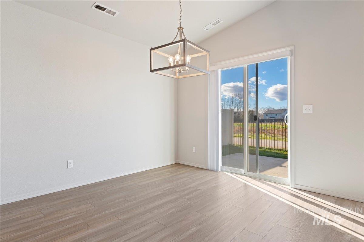 Unfurnished dining area featuring vaulted ceiling, wood finished floors, and a chandelier