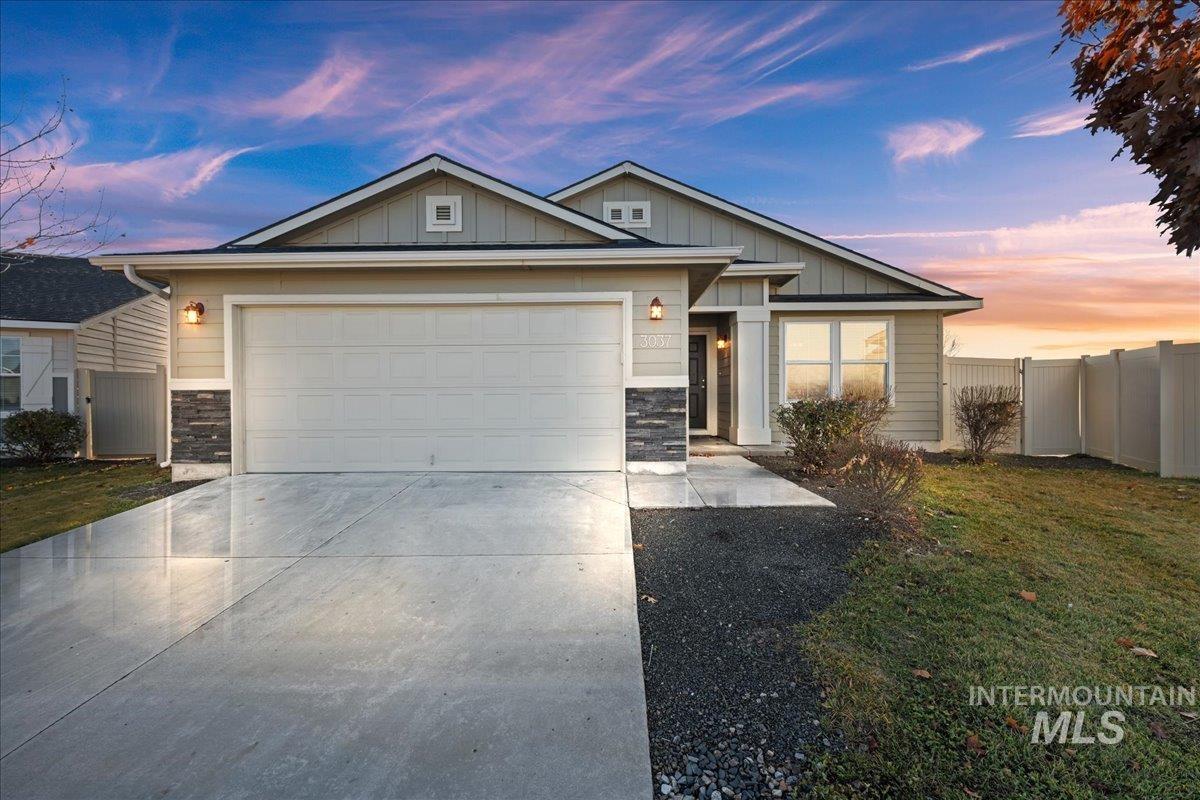 View of front facade with stone siding, driveway, board and batten siding, and a garage