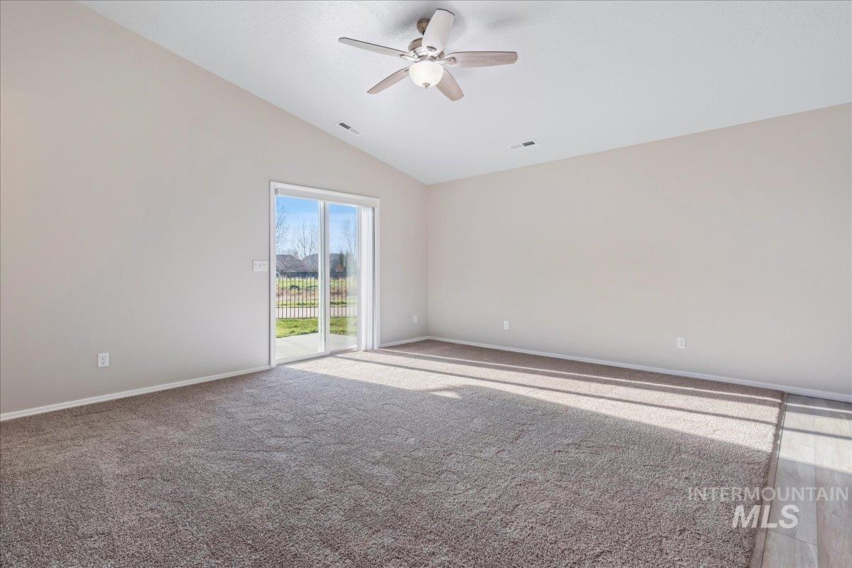 Carpeted empty room with vaulted ceiling and ceiling fan